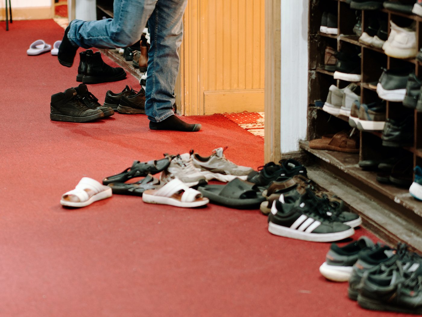 Shoes on the ground in cubby, with feet running in back