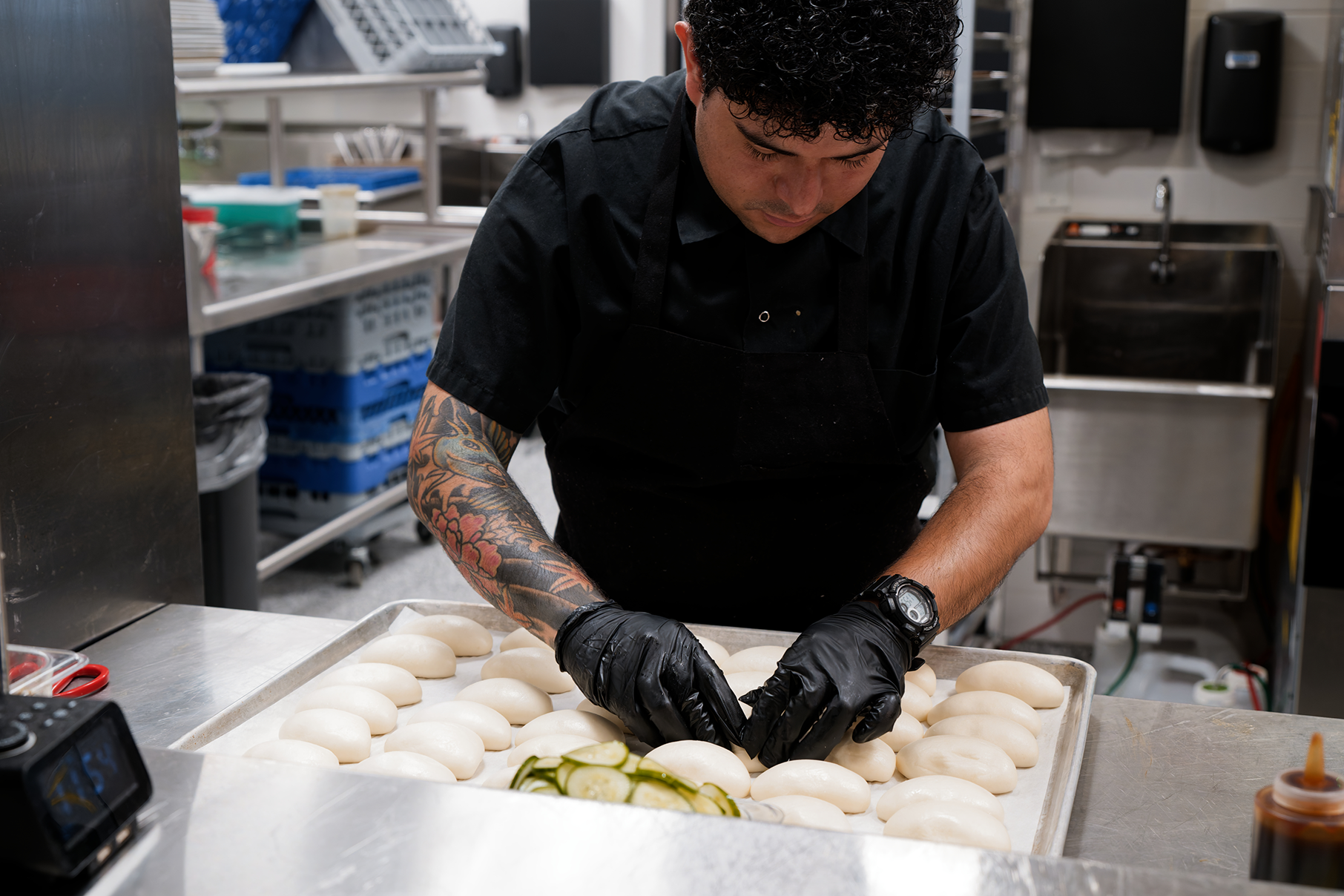A man in gloves assembles bao buns