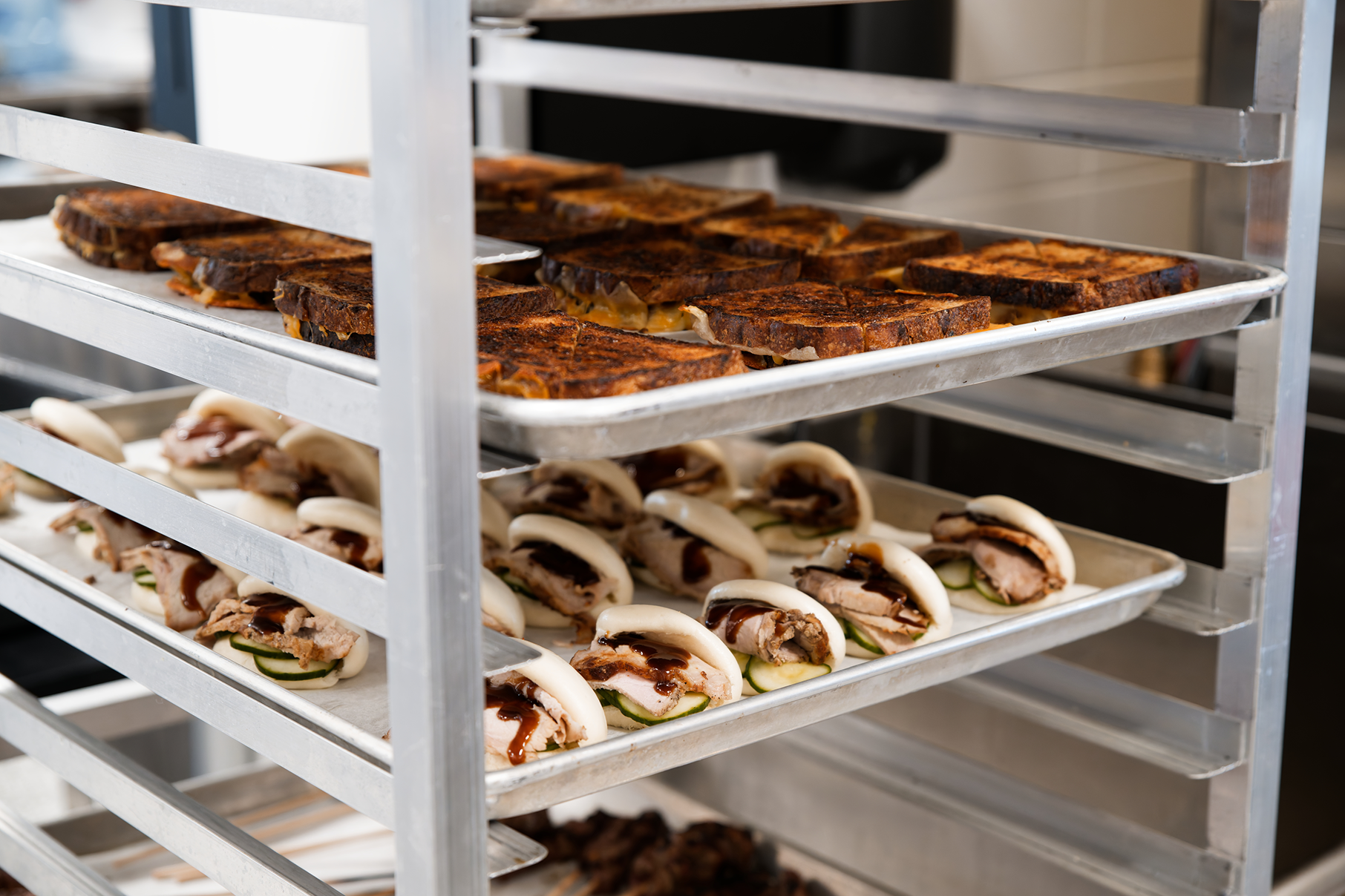 Trays of grilled cheese and pork bao buns in a rack