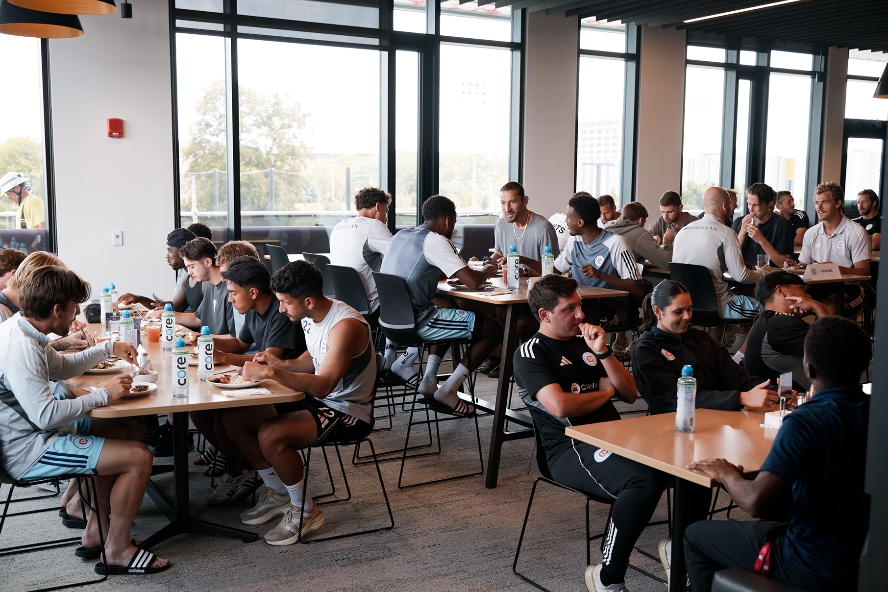 A group of athletes and staff eat in a cafeteria