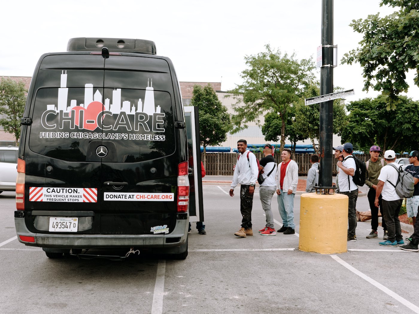 A line of men outside a black van labeled Chi-Care