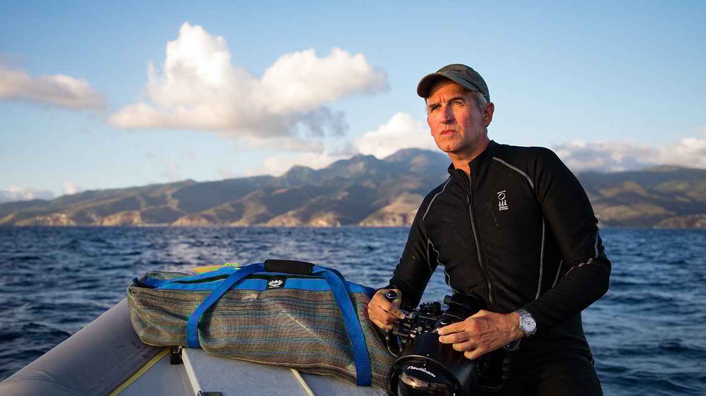 A diver sits on a boat and looks into the distance