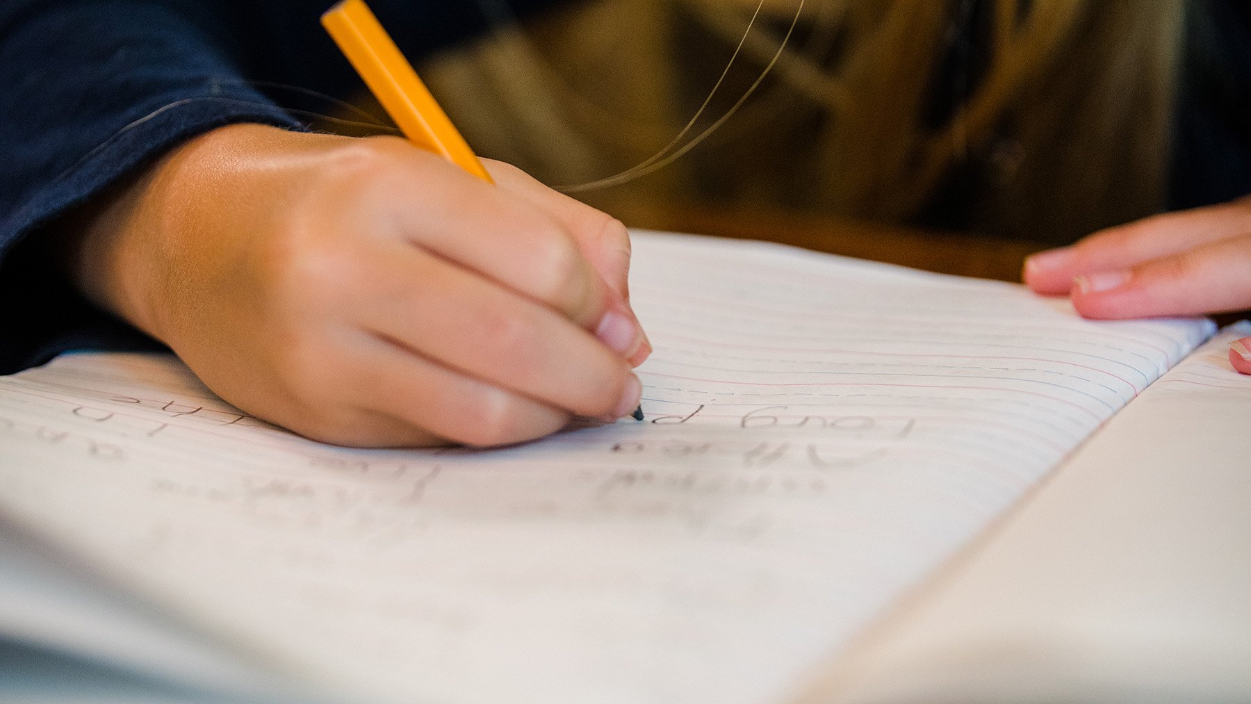 Closeup of student writing with a pensil in a notebook