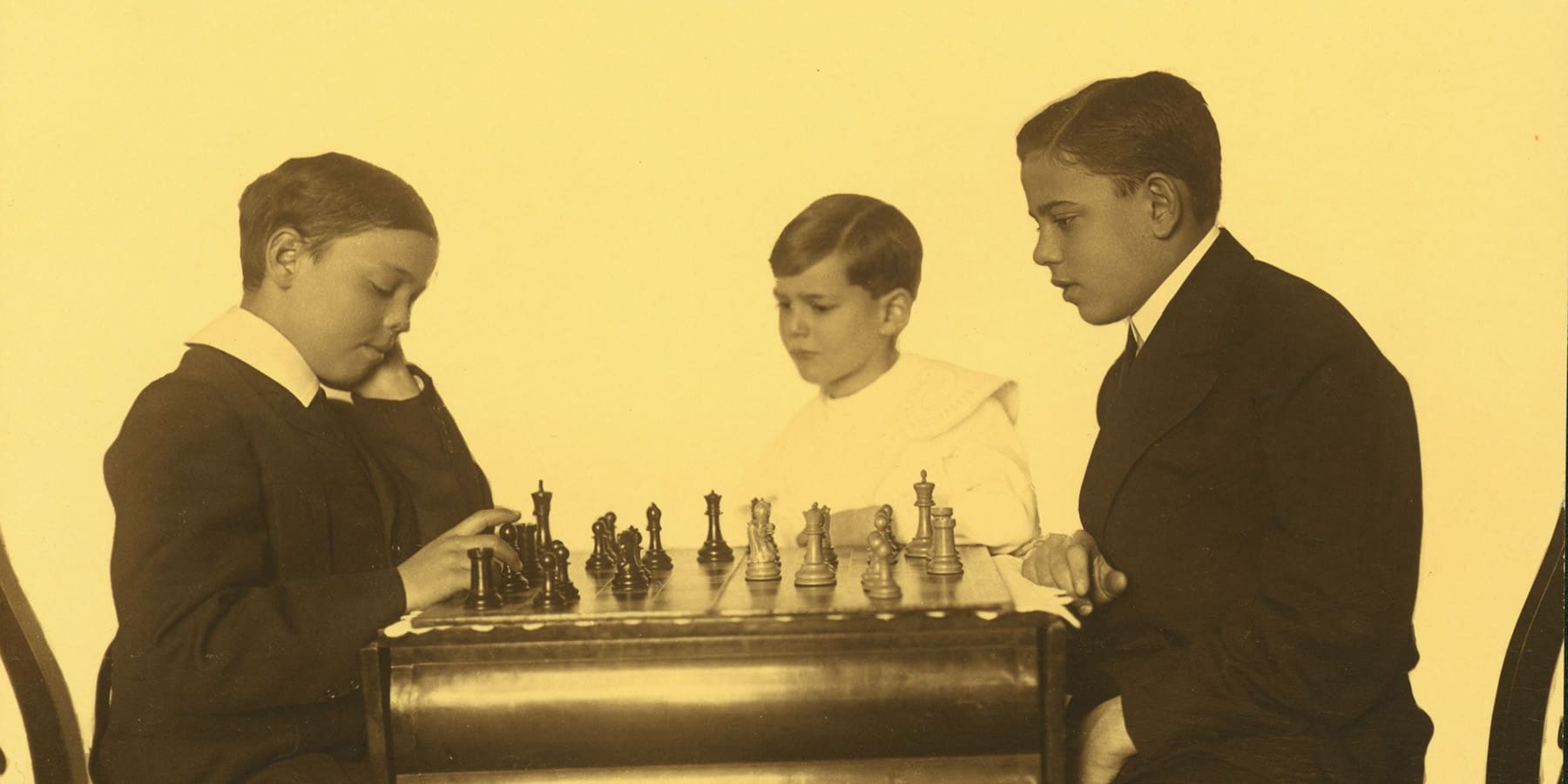 Richard Loeb, center, looks on as his older brothers Ernest and Allan play chess.
