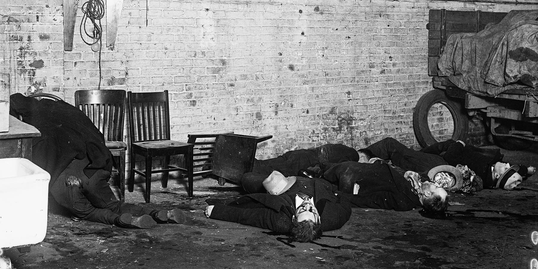Victims of the St. Valentine’s Day Massacre lay on the ground with blood visible on their faces and ground