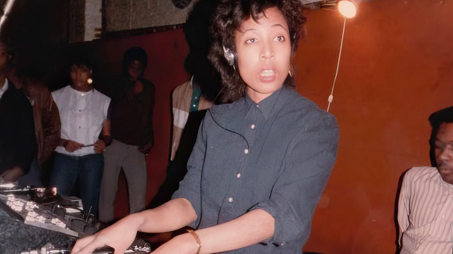 Lori Branch wearing headphones  places a record on a turntable 