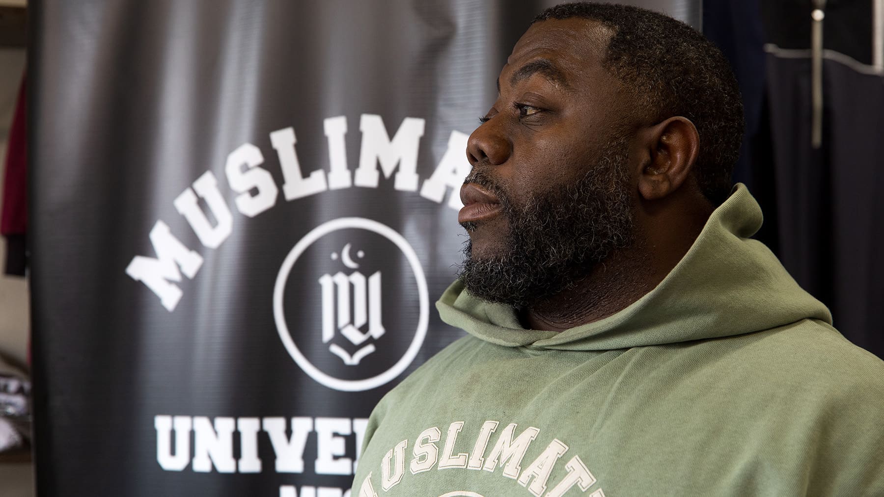 Kanoya Ali stands in front of a Muslimatic University banner