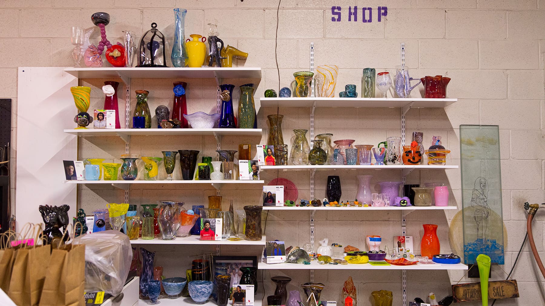 A colorful collection of glass vases and objects fill shelves.