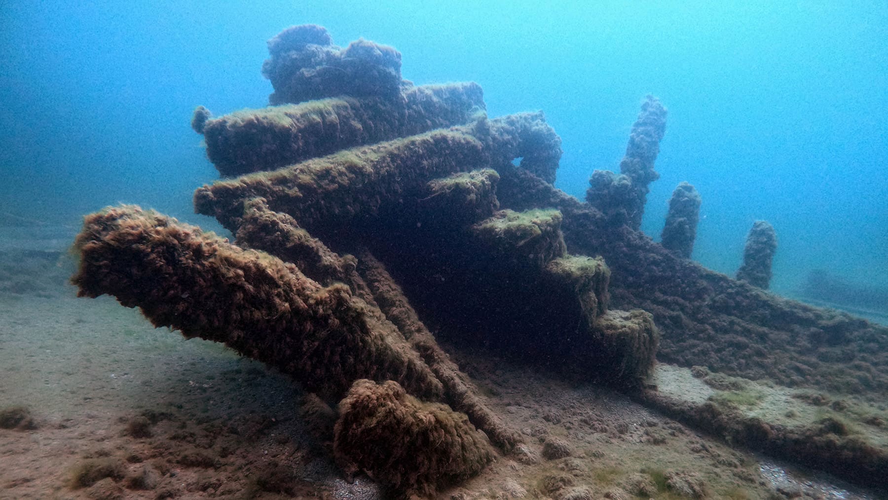 An underwater photo of a shipwreck partially submerged at the bottom of Lake Michigan.