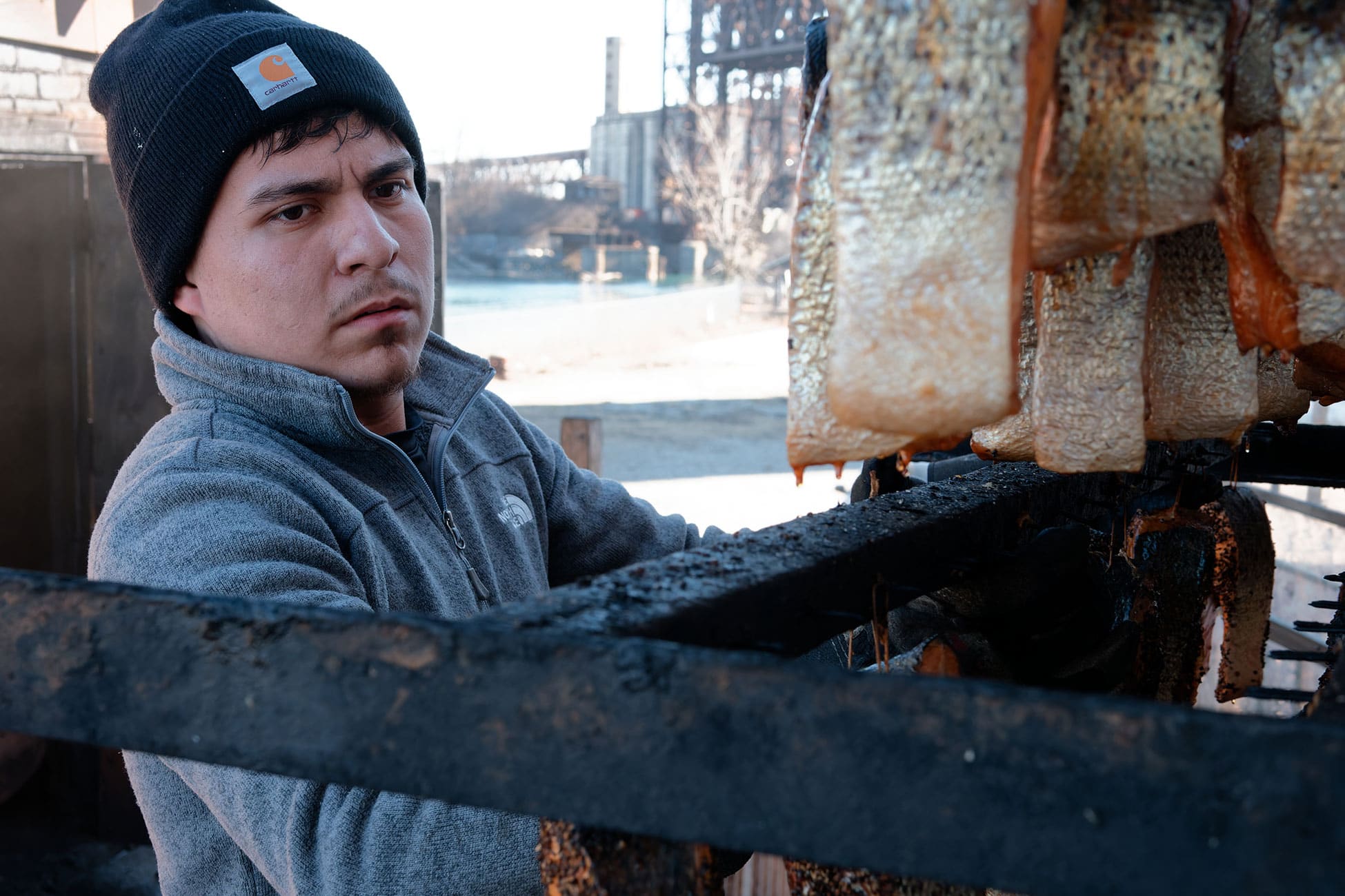 A worker pulls a rack of fish out of the smokehouse.