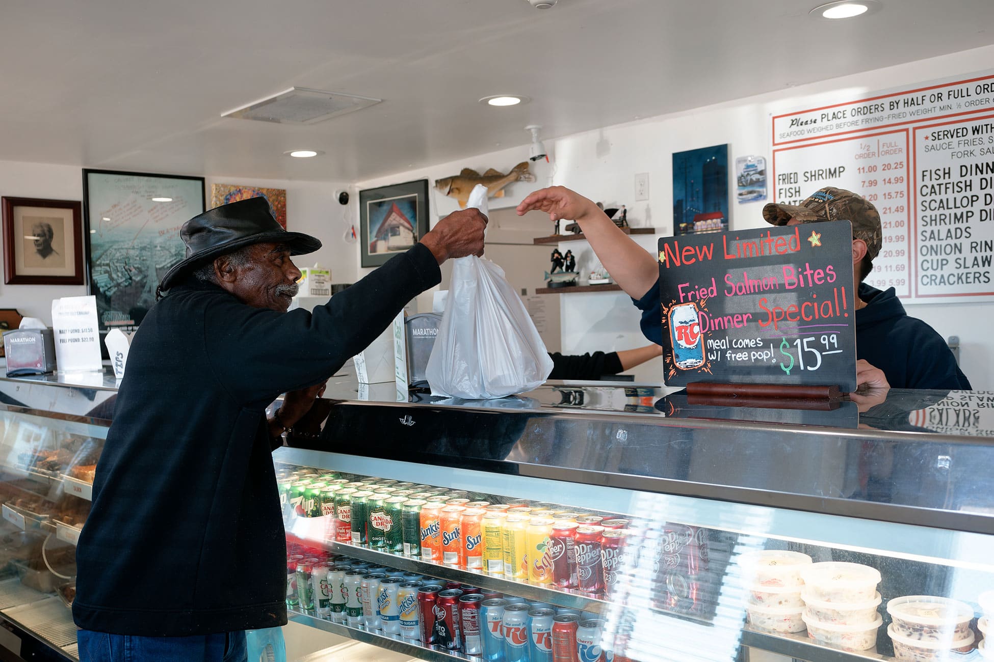 A worker hands a plastic bag of food over the counter to a customer.