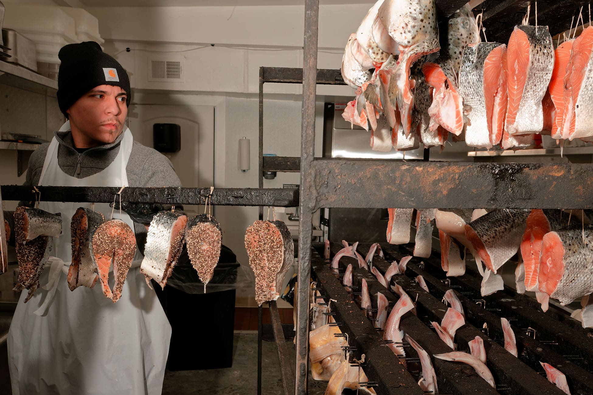 Pieces of seasond fish hang from racks.