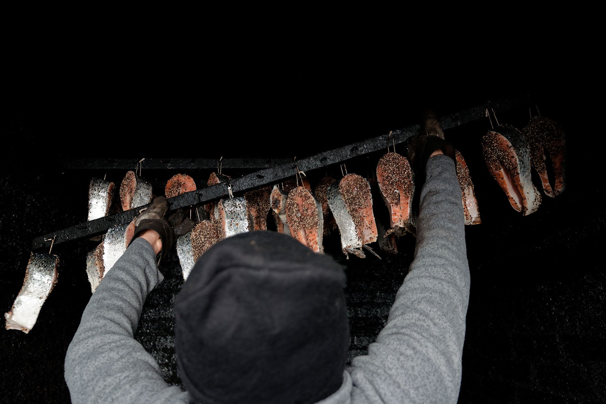 A rack of seasoned fish gets hung in the smokehouse.