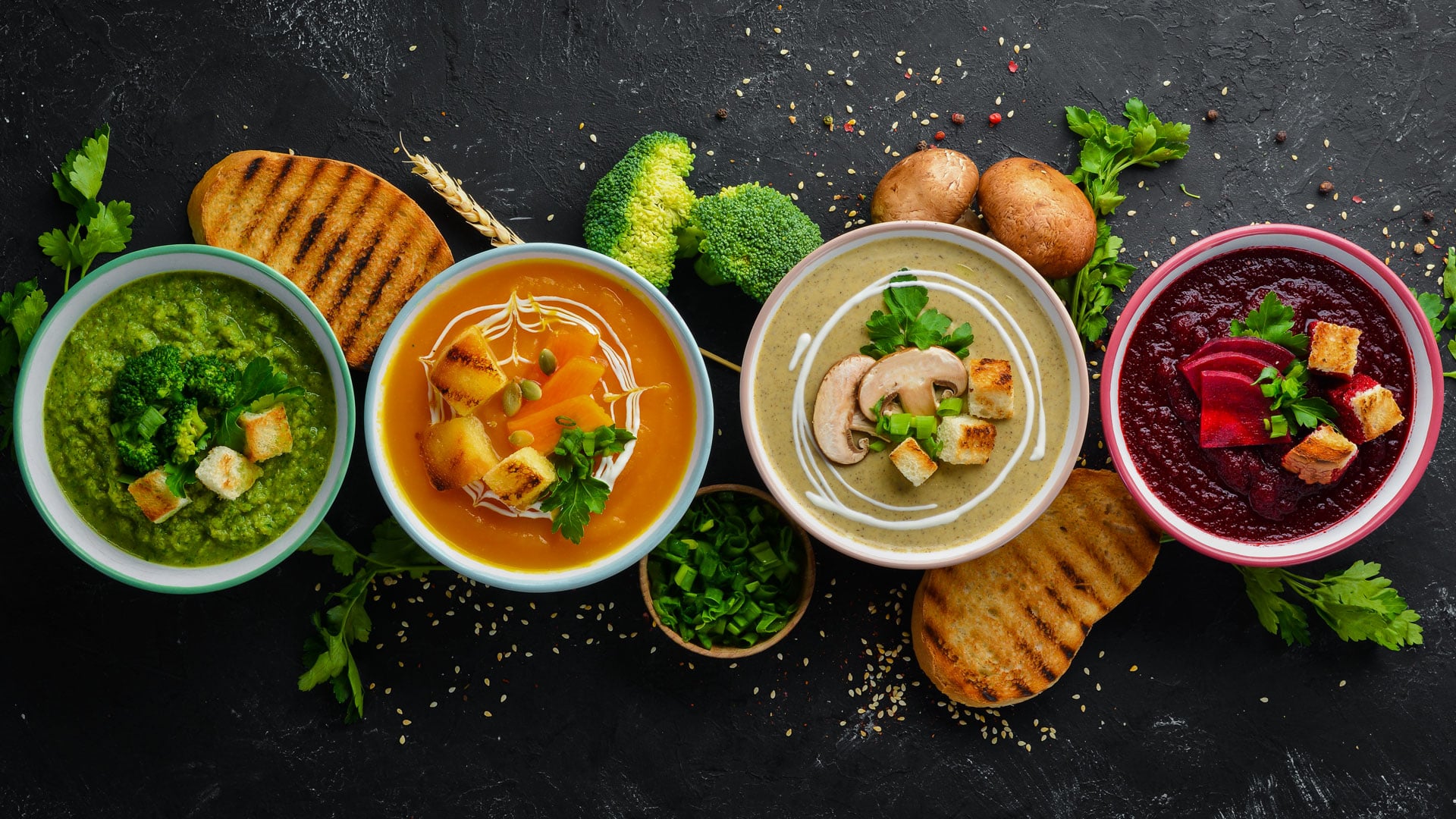 Four colorful bowls of foods and ingredients are displayed on a black tabletop