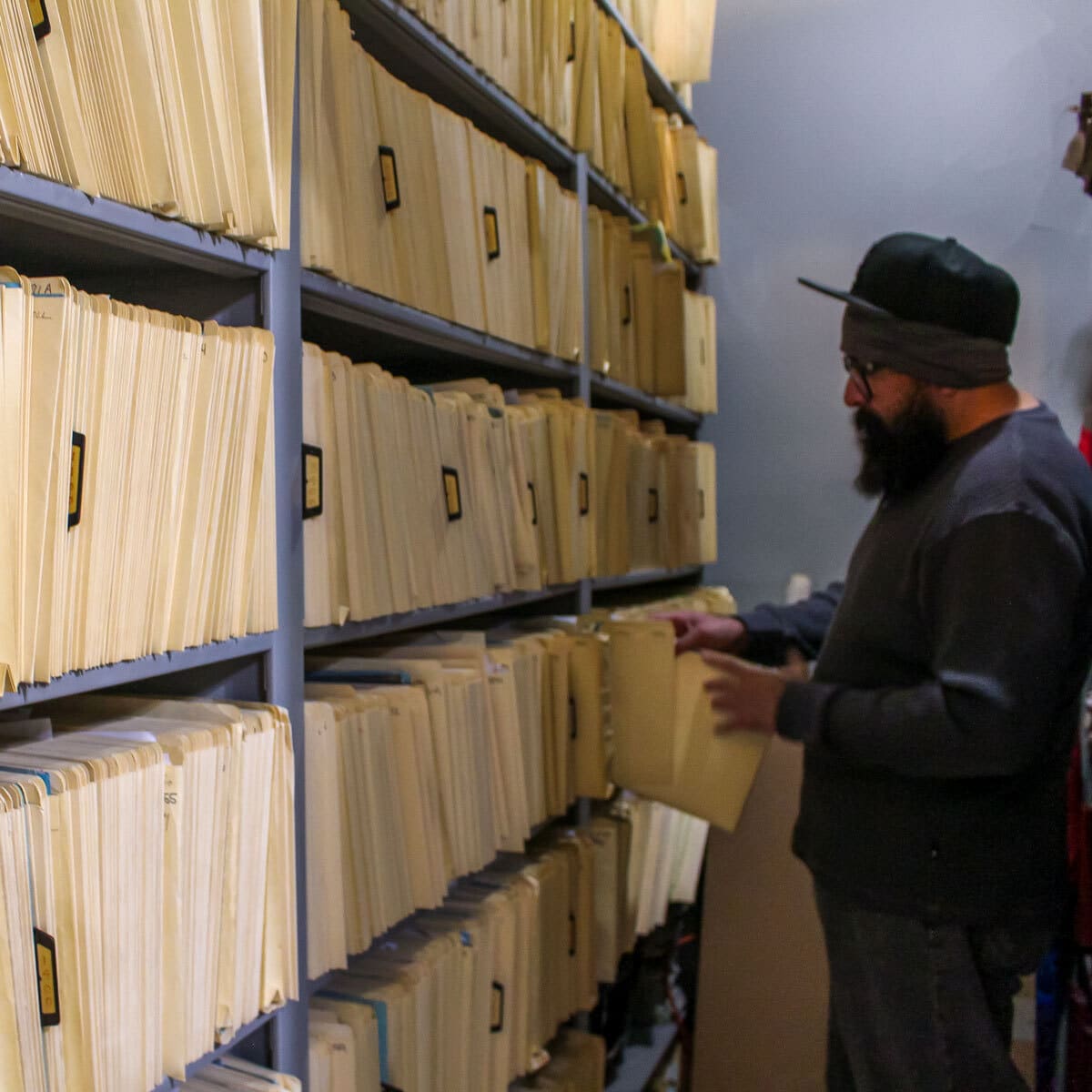 A man places a folder into a shelf full of folders