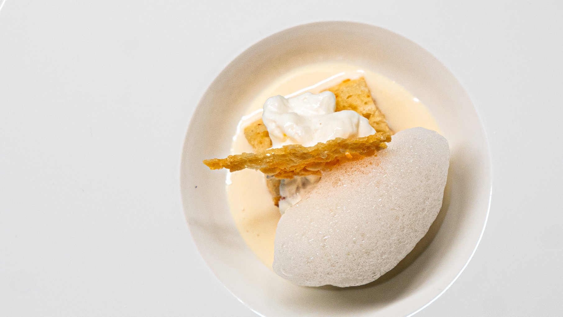 A dish of cheese presented as foam, cracker, sauce, and more