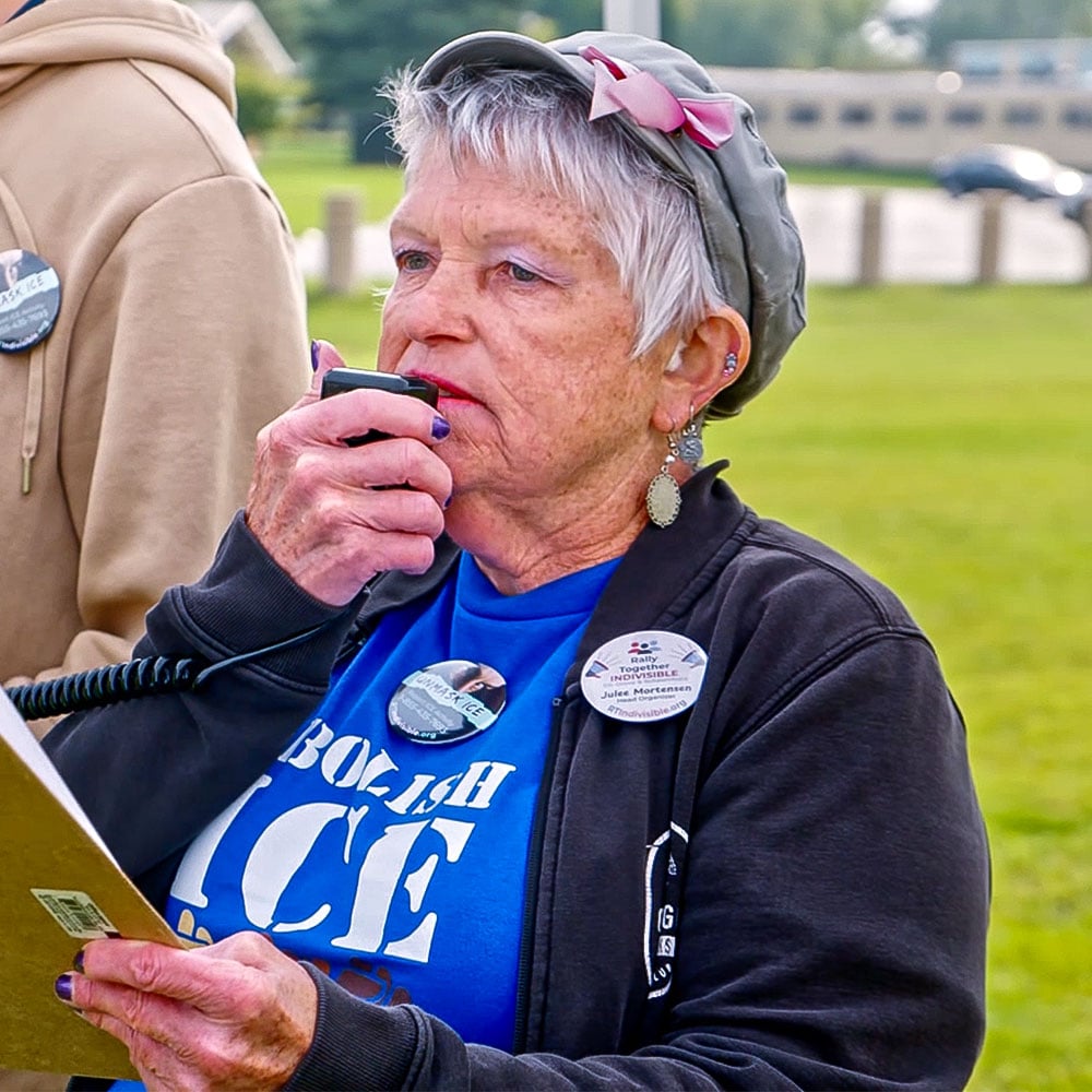 Julee with 'Abolish ICE' shirt and buttons on speaking into a megaphone