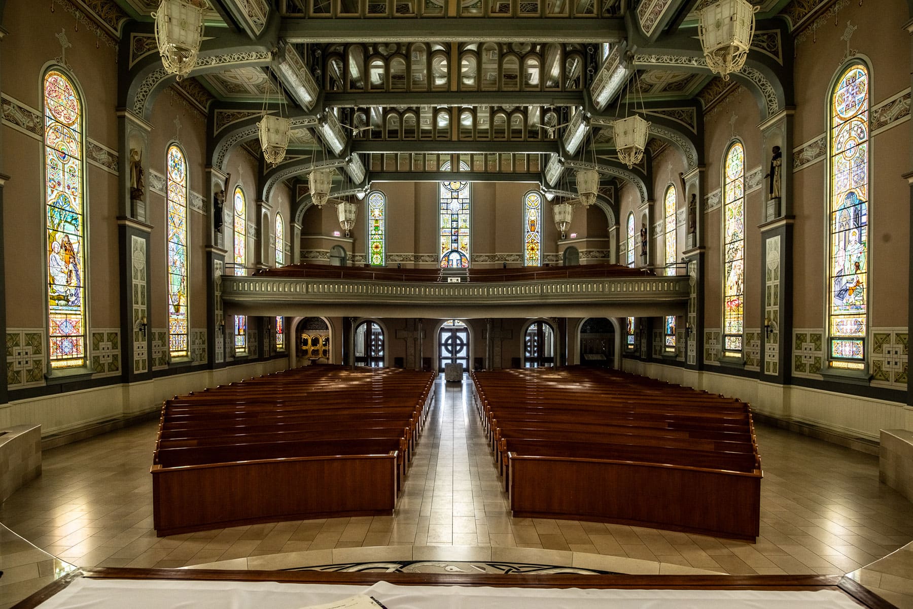 Interior view of the Old St. Patrick's Church sanctuary, looking from the altar down a central aisle between rows of polished wooden pews toward the rear entrance.