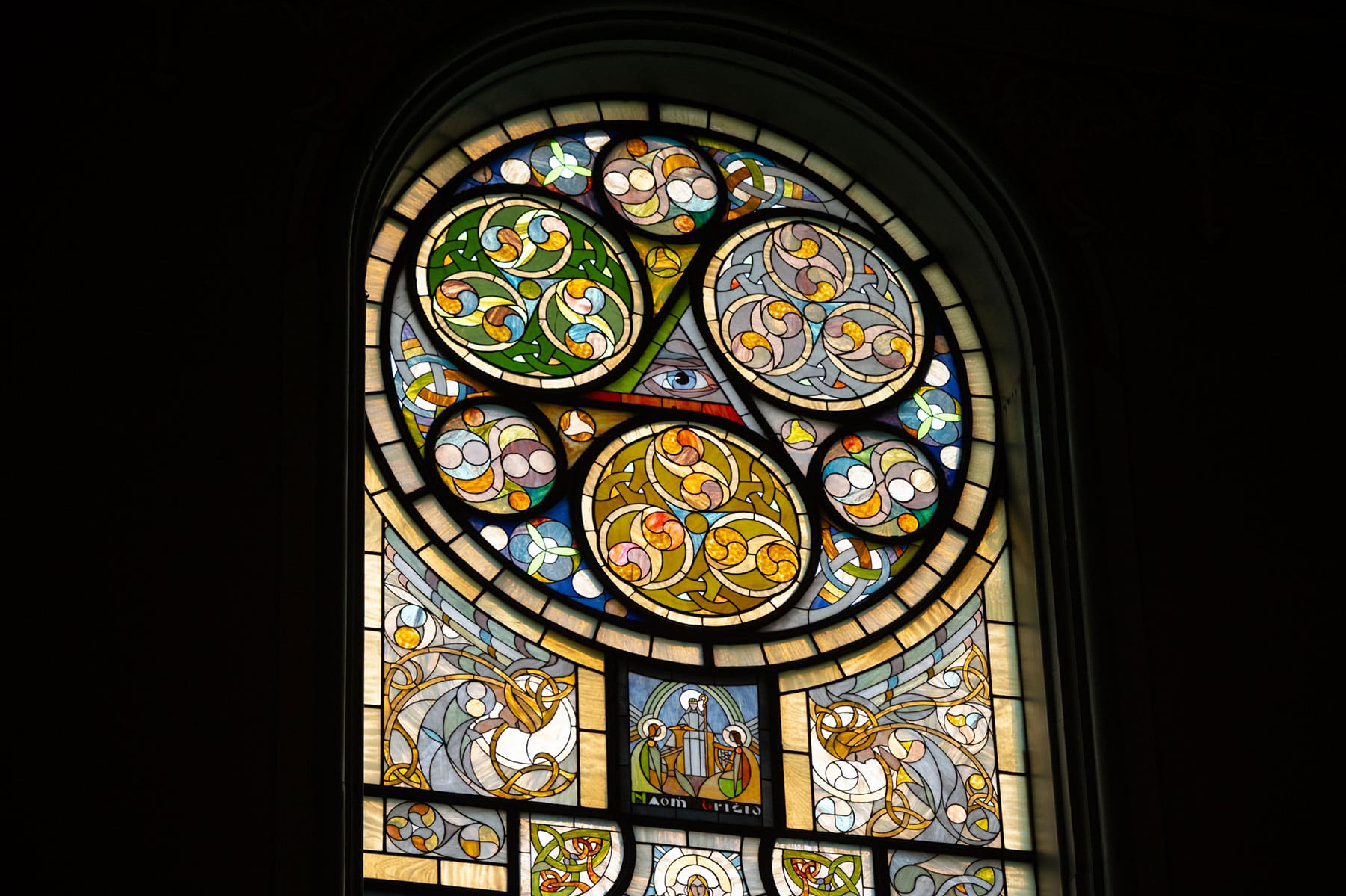 Celtic-style stained glass window featuring intricate interlacing patterns and an eye symbol, designed by artist Thomas O'Shaughnessy at Old St. Patrick's Church
