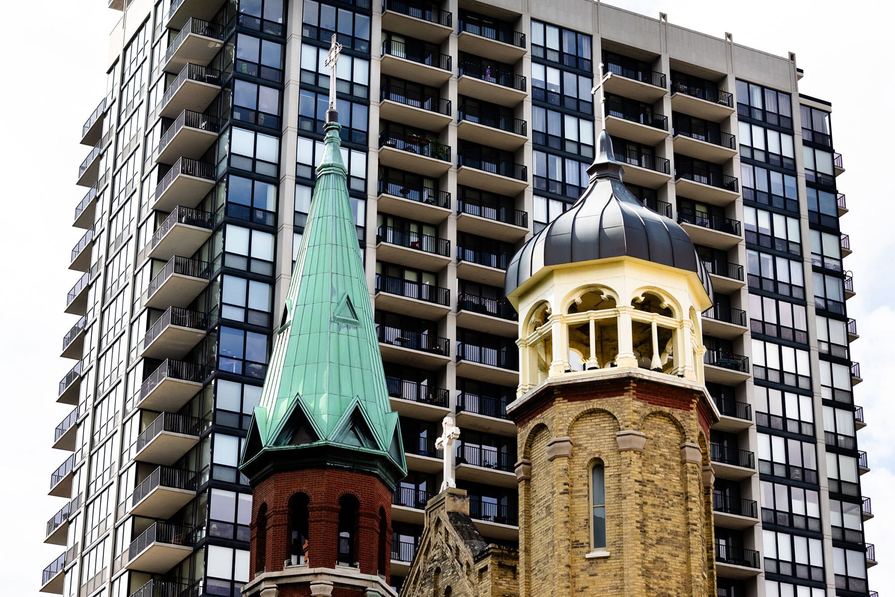 The towers of Old St. Patrick's Church with a tall apartment building with balconies in the background