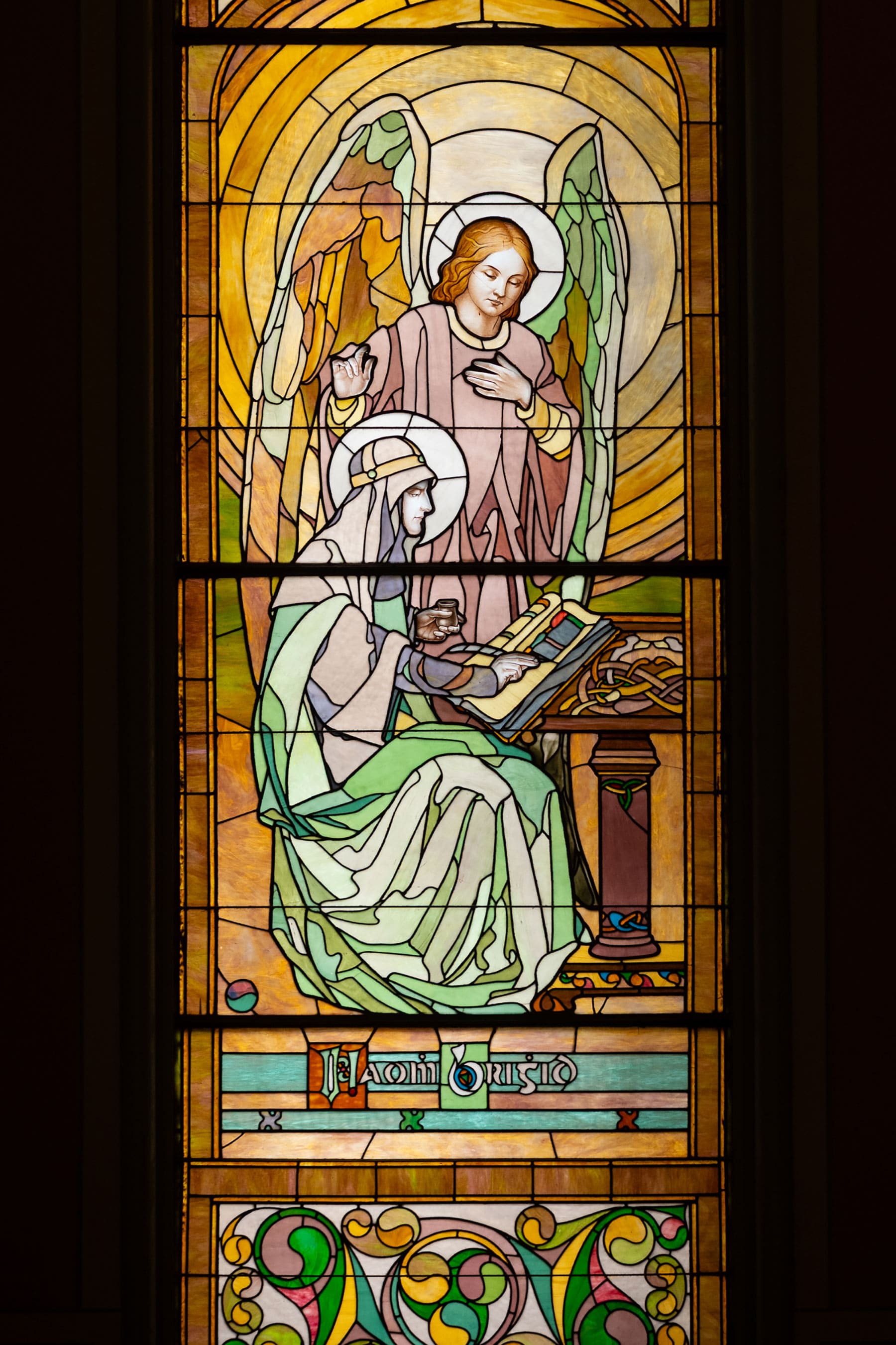 Closeup of the stained glass window depicting an angel instructing a seated saint