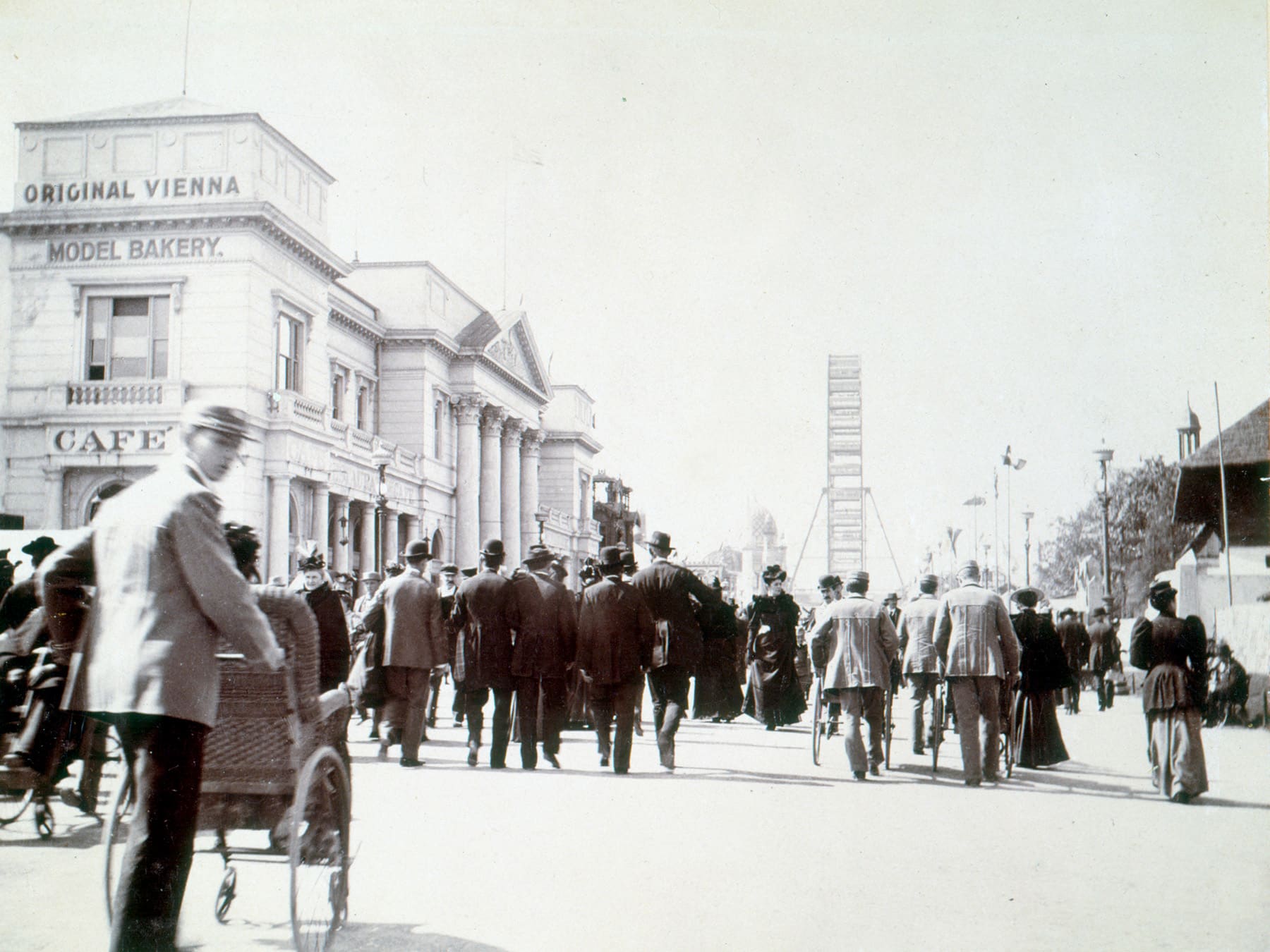 Crowds walk the Midway Plaisance toward the Ferris wheel.