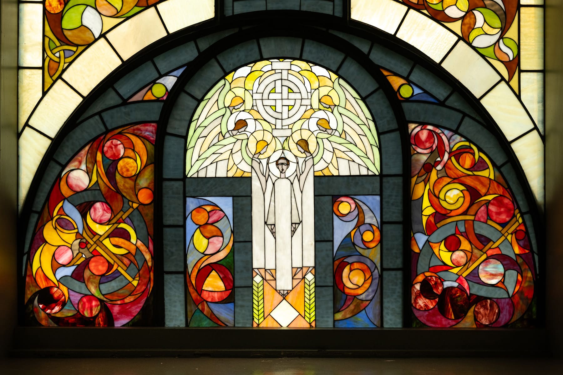 The middle section of the MacSwiney window prominently displaying ornate, illuminated text panels that read