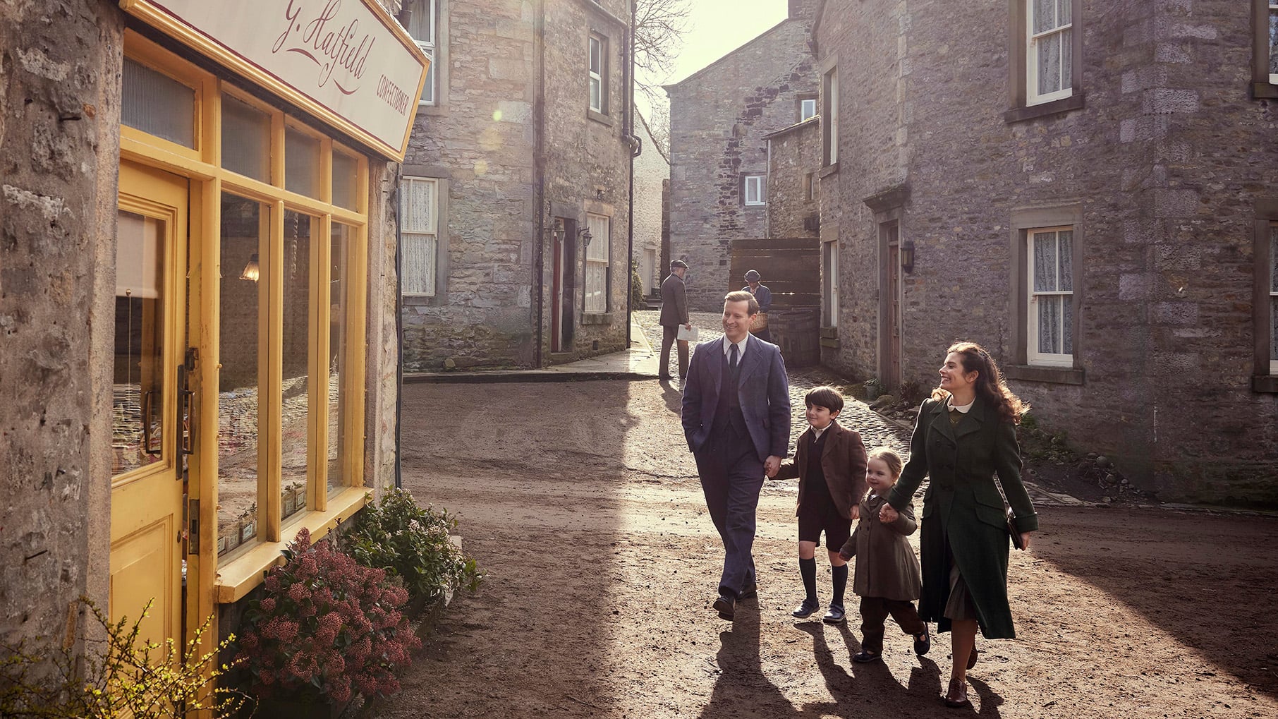 James and Helen walk down a small-town street with their two children