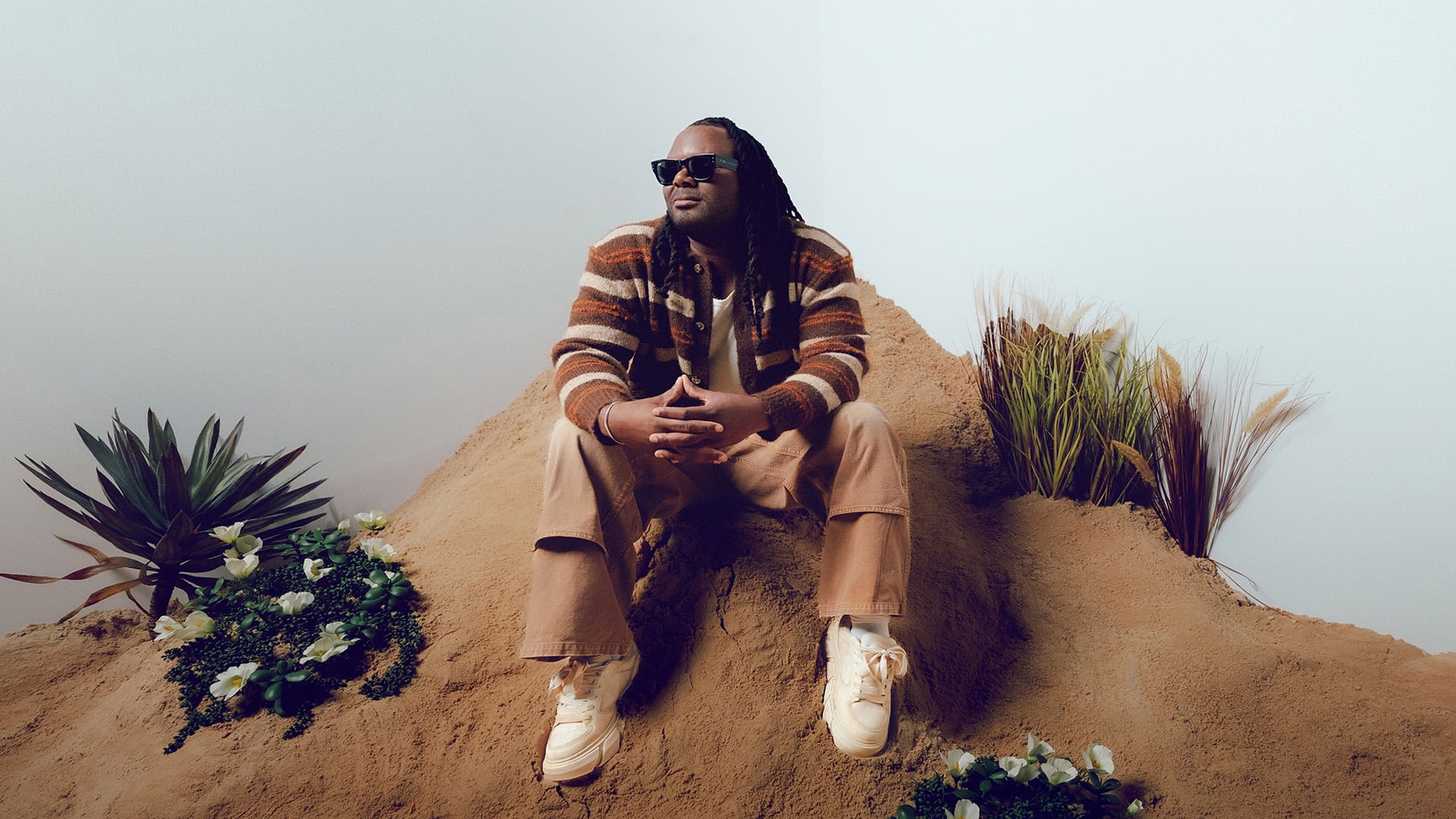 Blessing Offor sits on a pile of sand in sunglasses