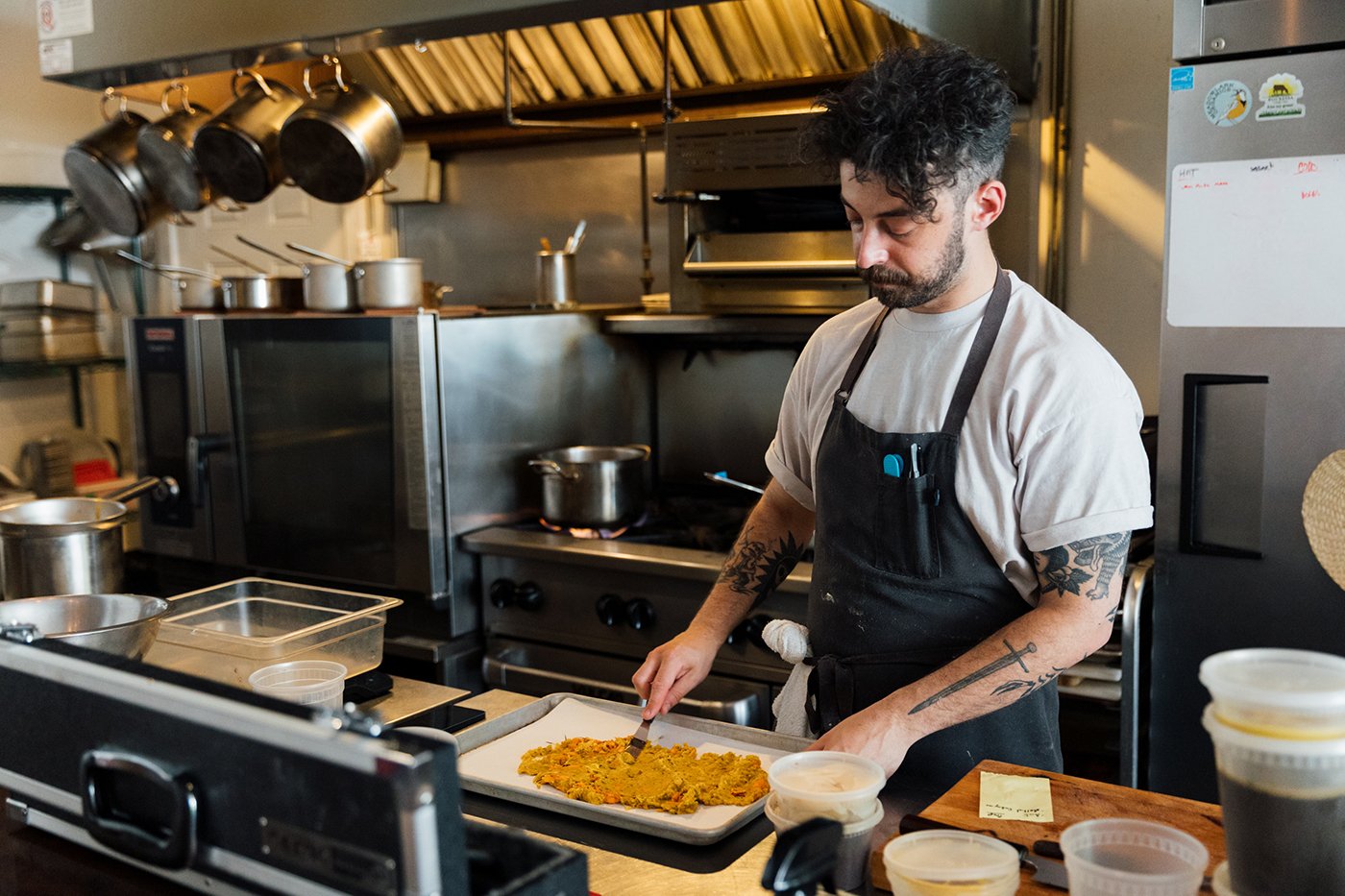Alex Cochran spreads an orange mixture on a sheet pan