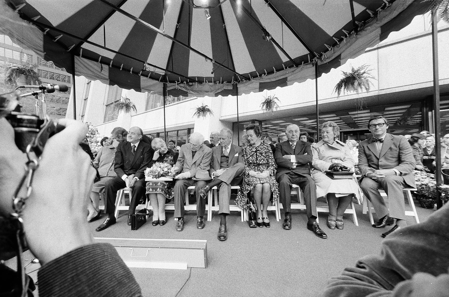 A black and white photo of a row of dignitaries sitting under a covering, including Marc Chagall and Chicago mayor Richard J. Daley