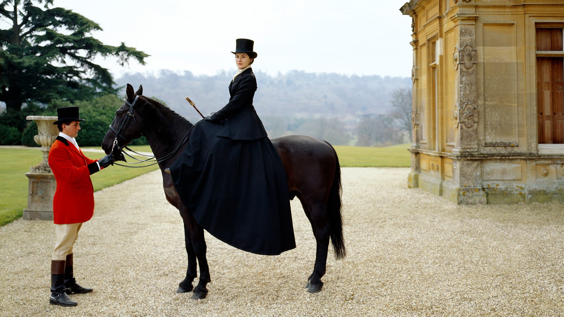 Mary sits on a horse in a top hat while a groom handles the horse