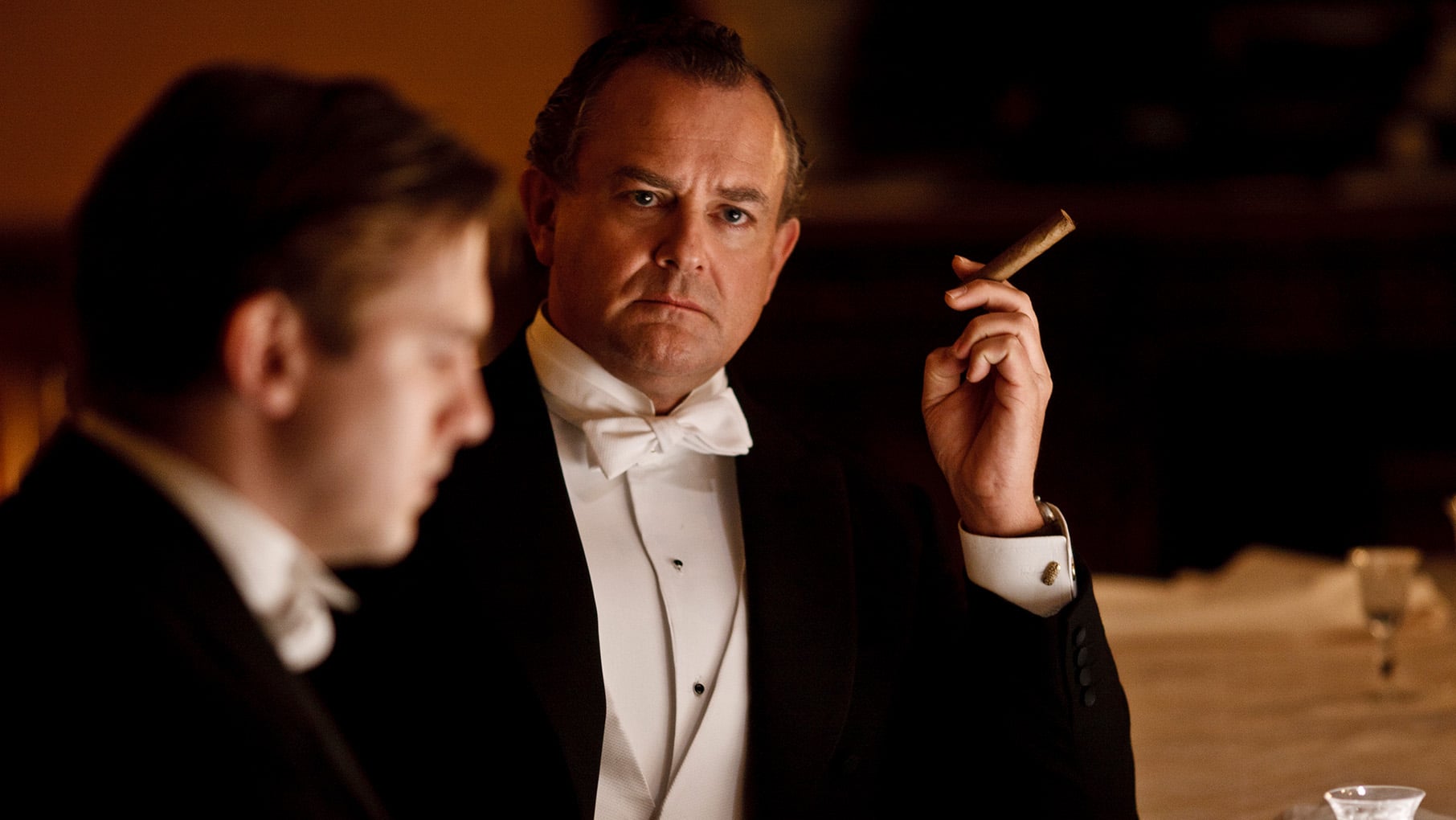 Robert smokes a cigar in a tuxedo with Matthew