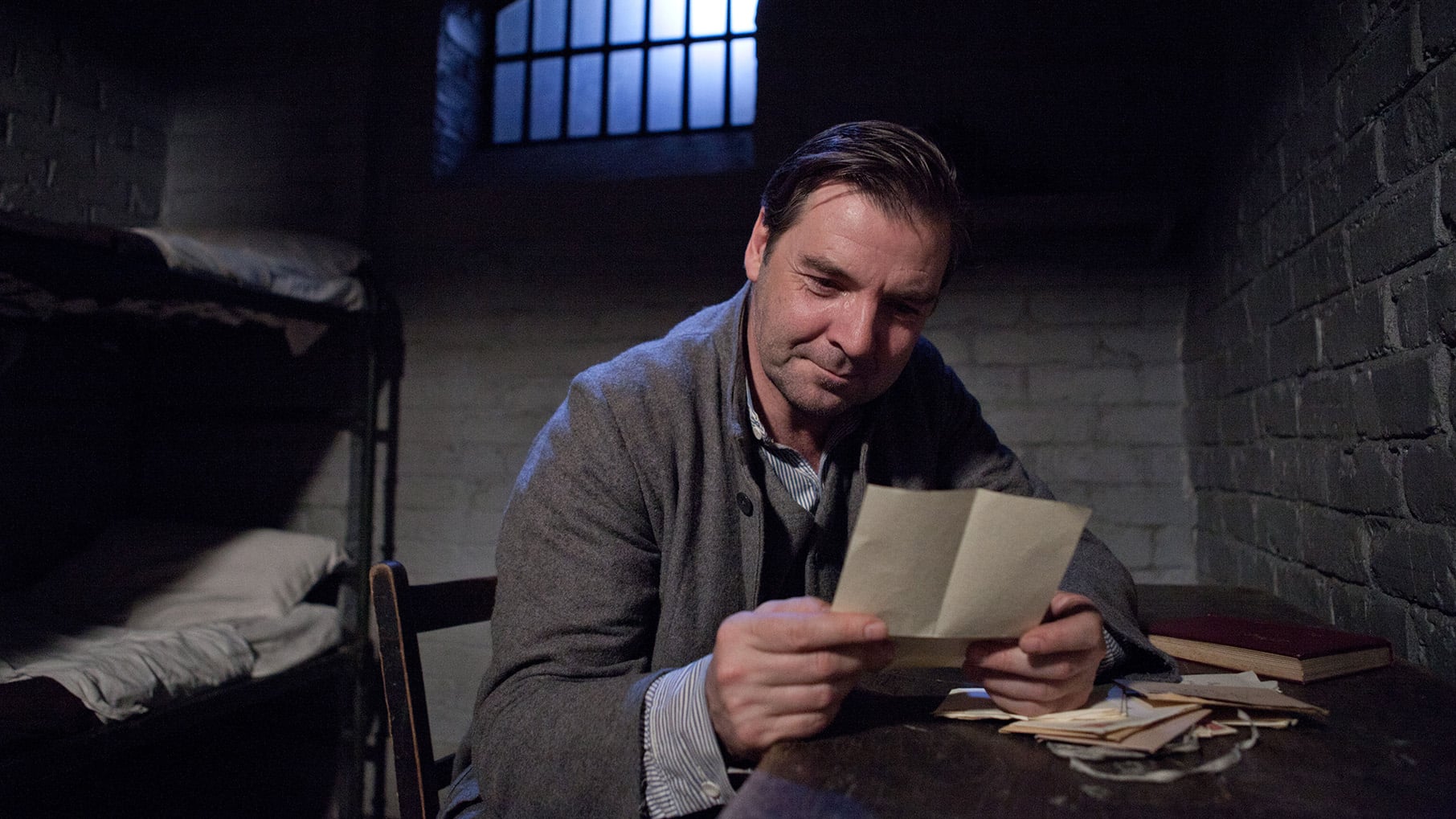 Bates smiles while reading a letter in prison