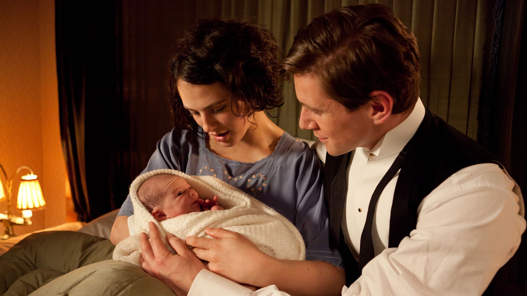 Sybil holds her newborn baby with Tom in bed