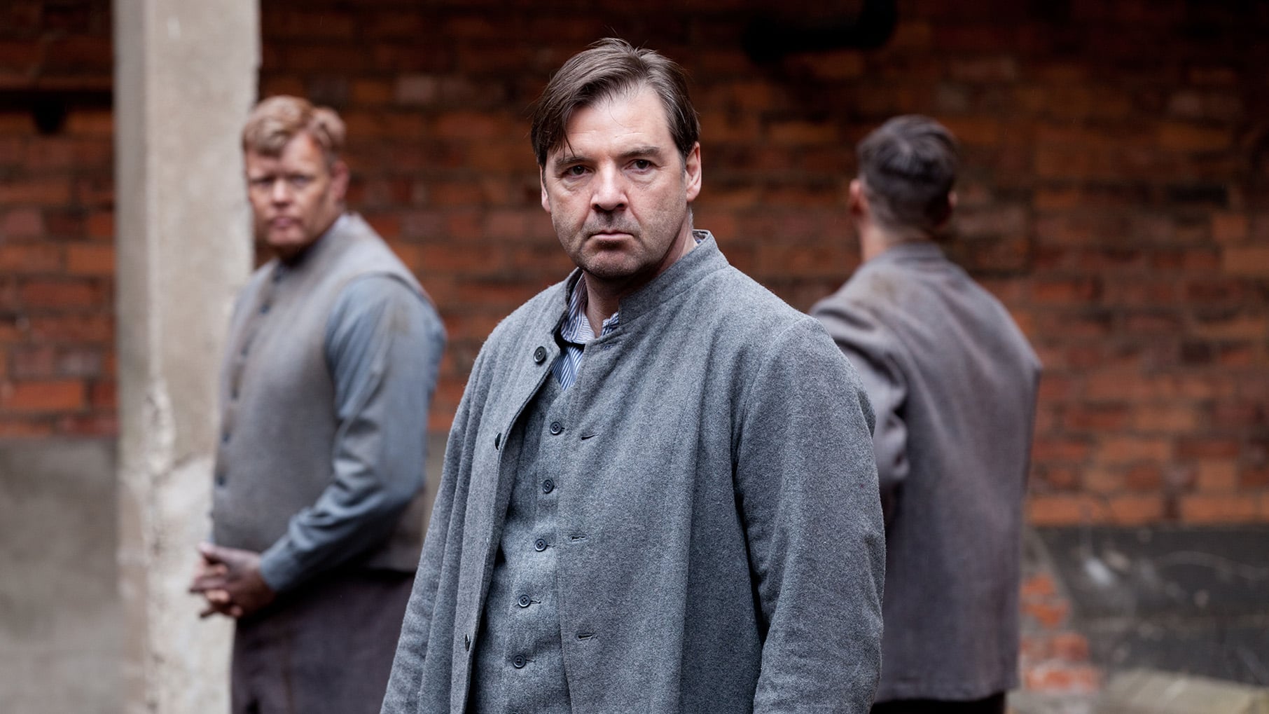 Bates stands in a prison uniform