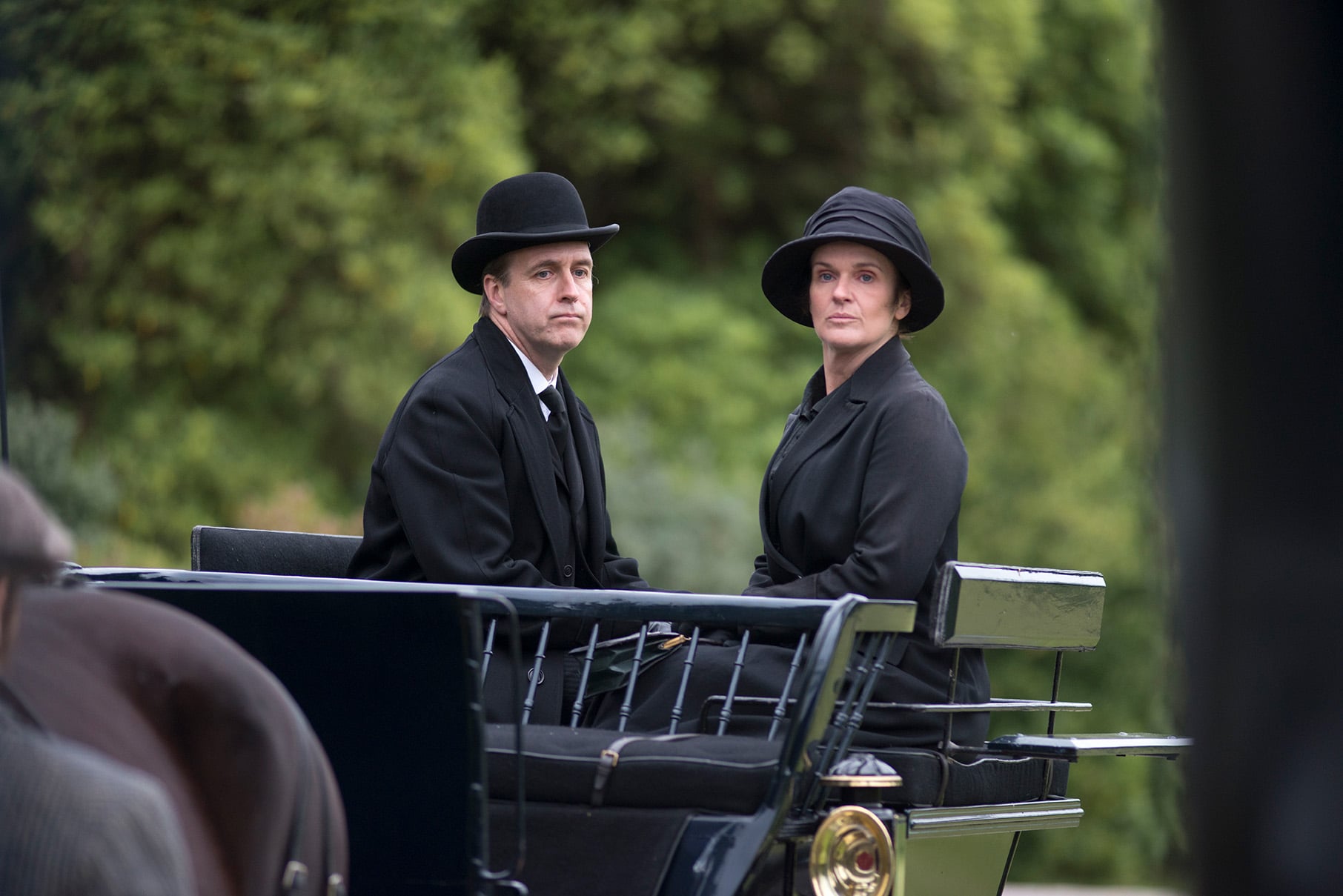 Molesley and O'Brien sit glumly in black in a carriage
