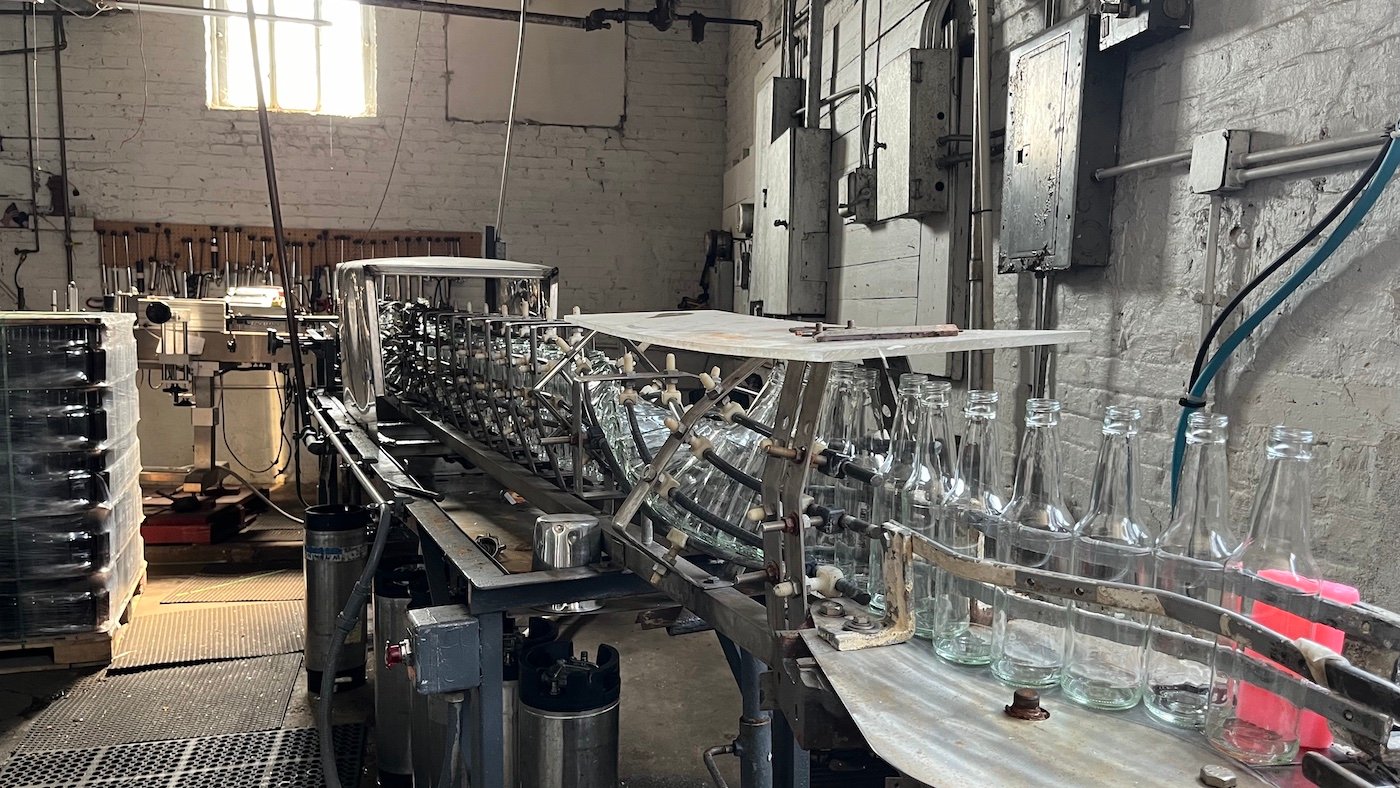 A line of bottles on an assembly line in a brick building