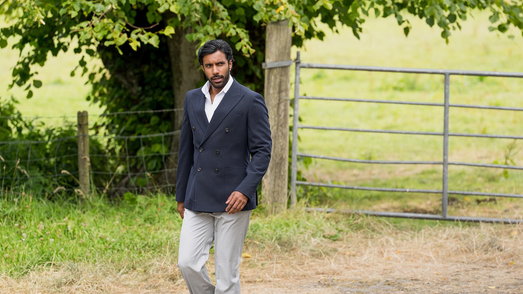 Rishi Nair walks down a lane in a double breasted jacket