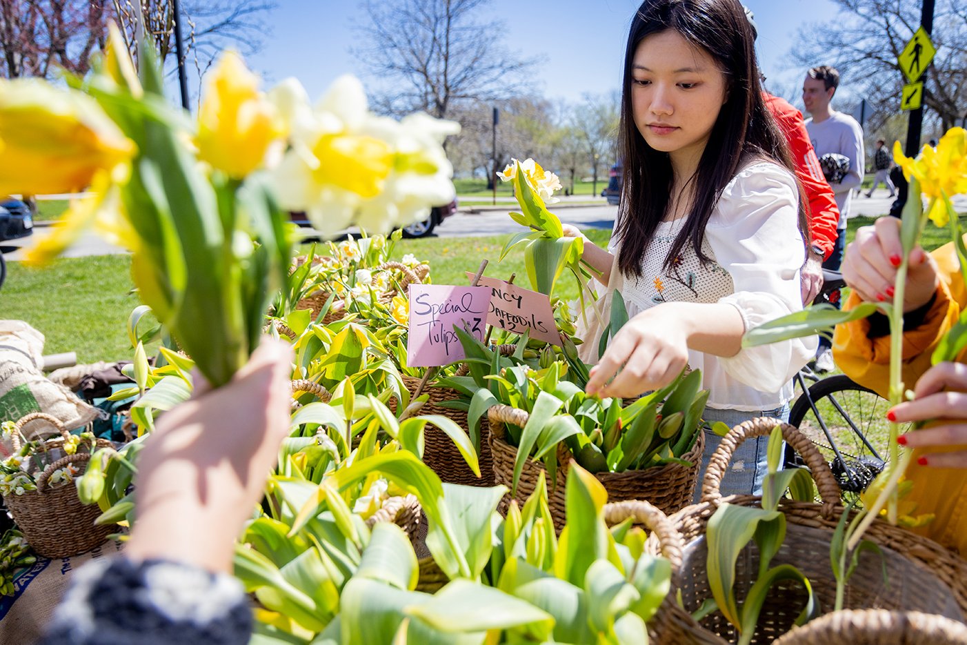 A woman selects flowers from baskets outside