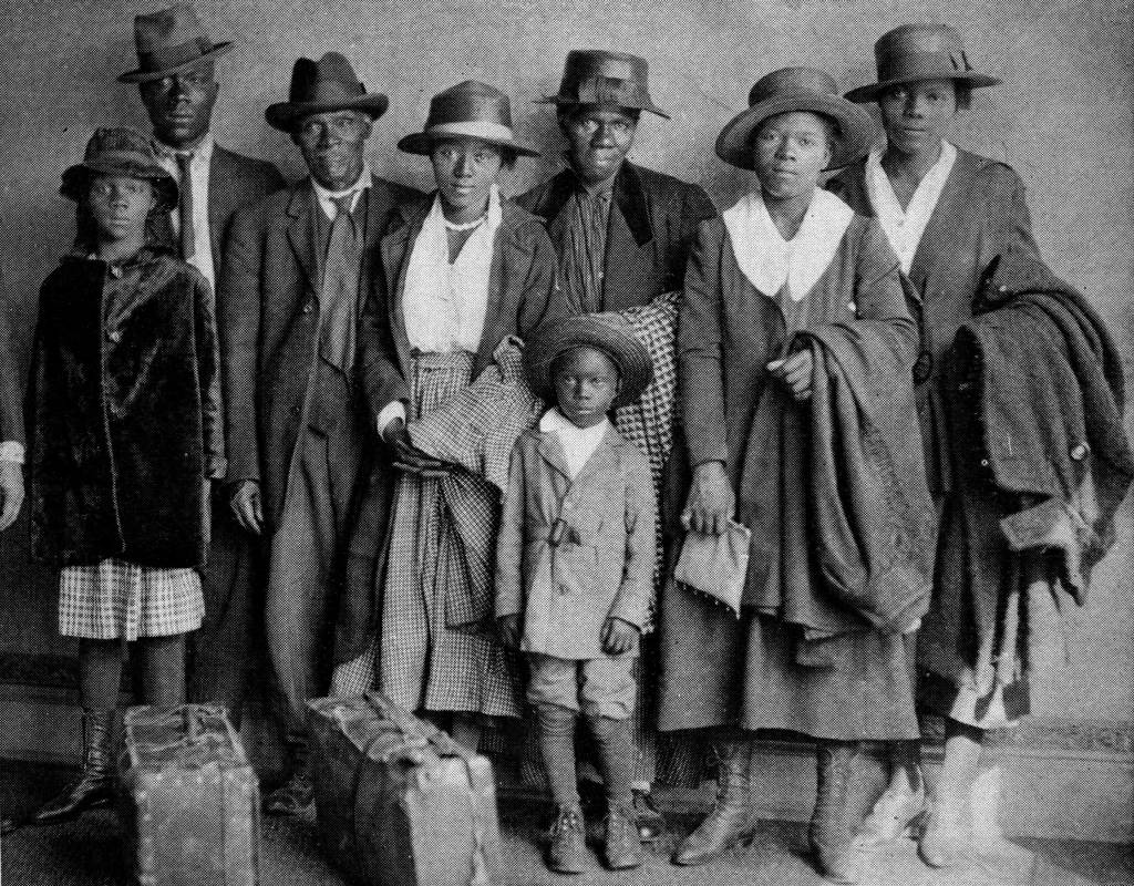 A Black family poses together with suitcases in a black and white photo