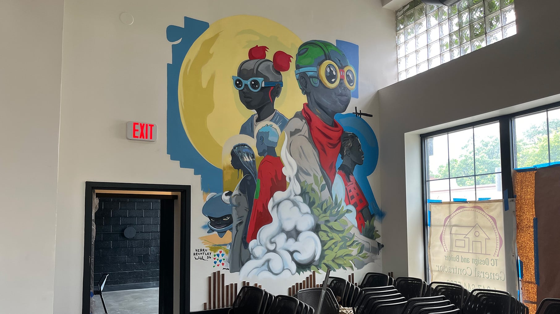 A mural of Black children in superhero-like costumes between a door and windows