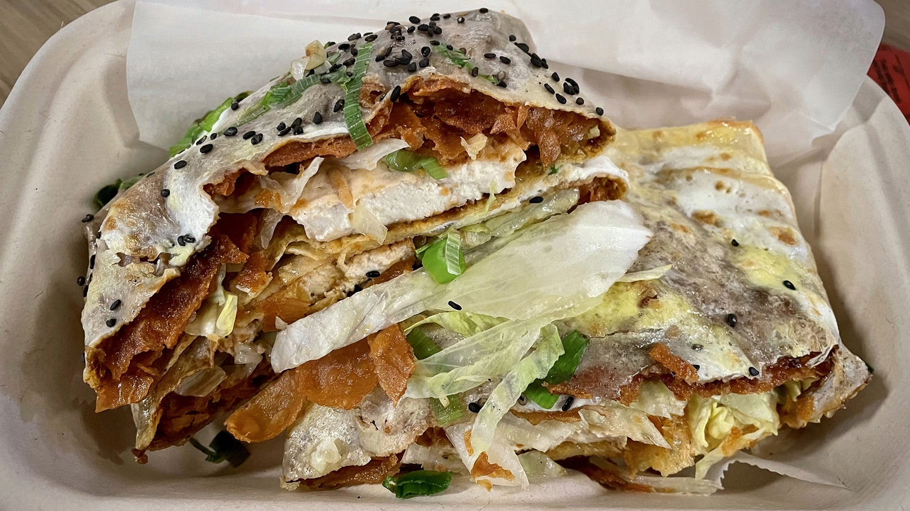 A crepe wrapped around tofu, lettuce, egg, and more