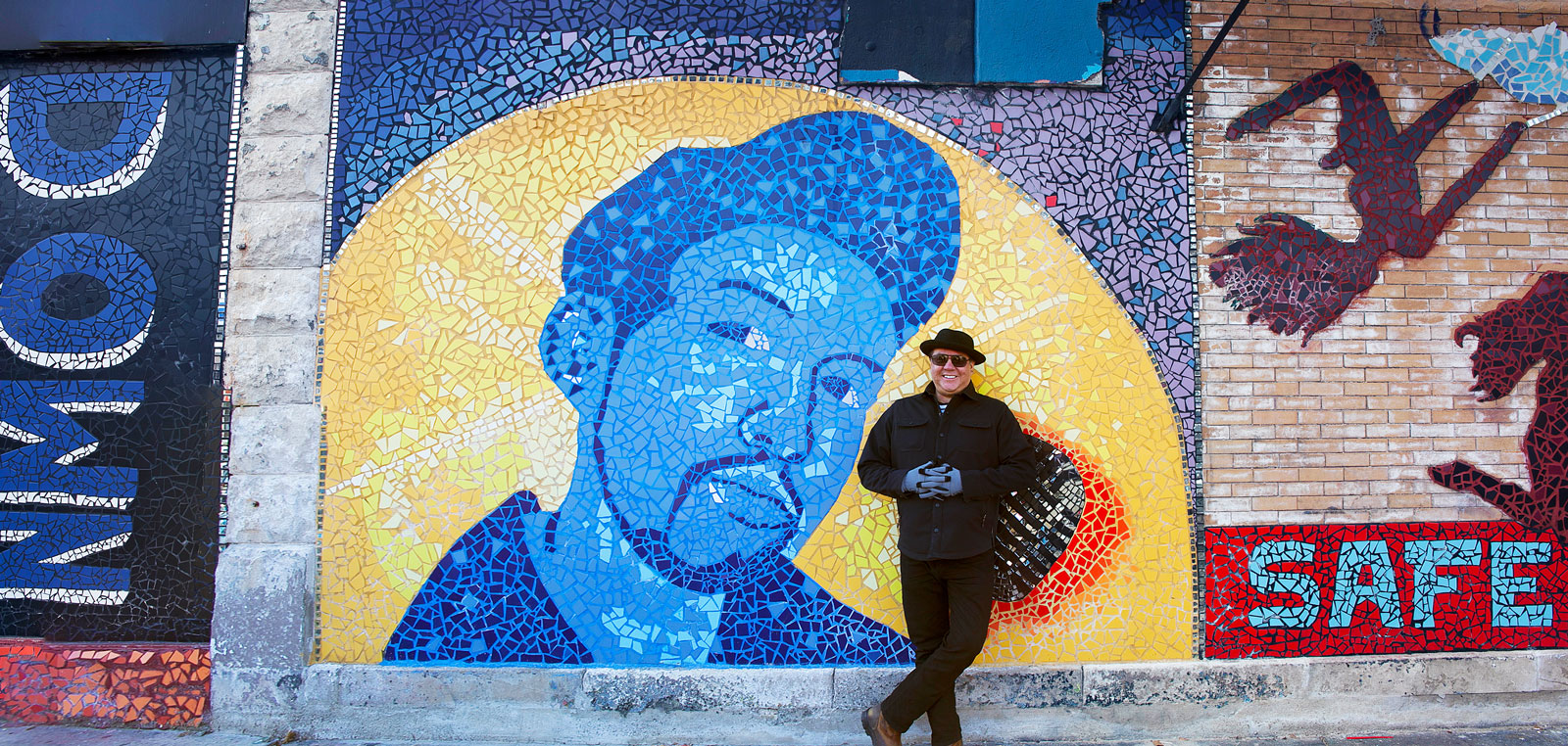 Jeff Maldonado stands with the J-Def Peace Project mural