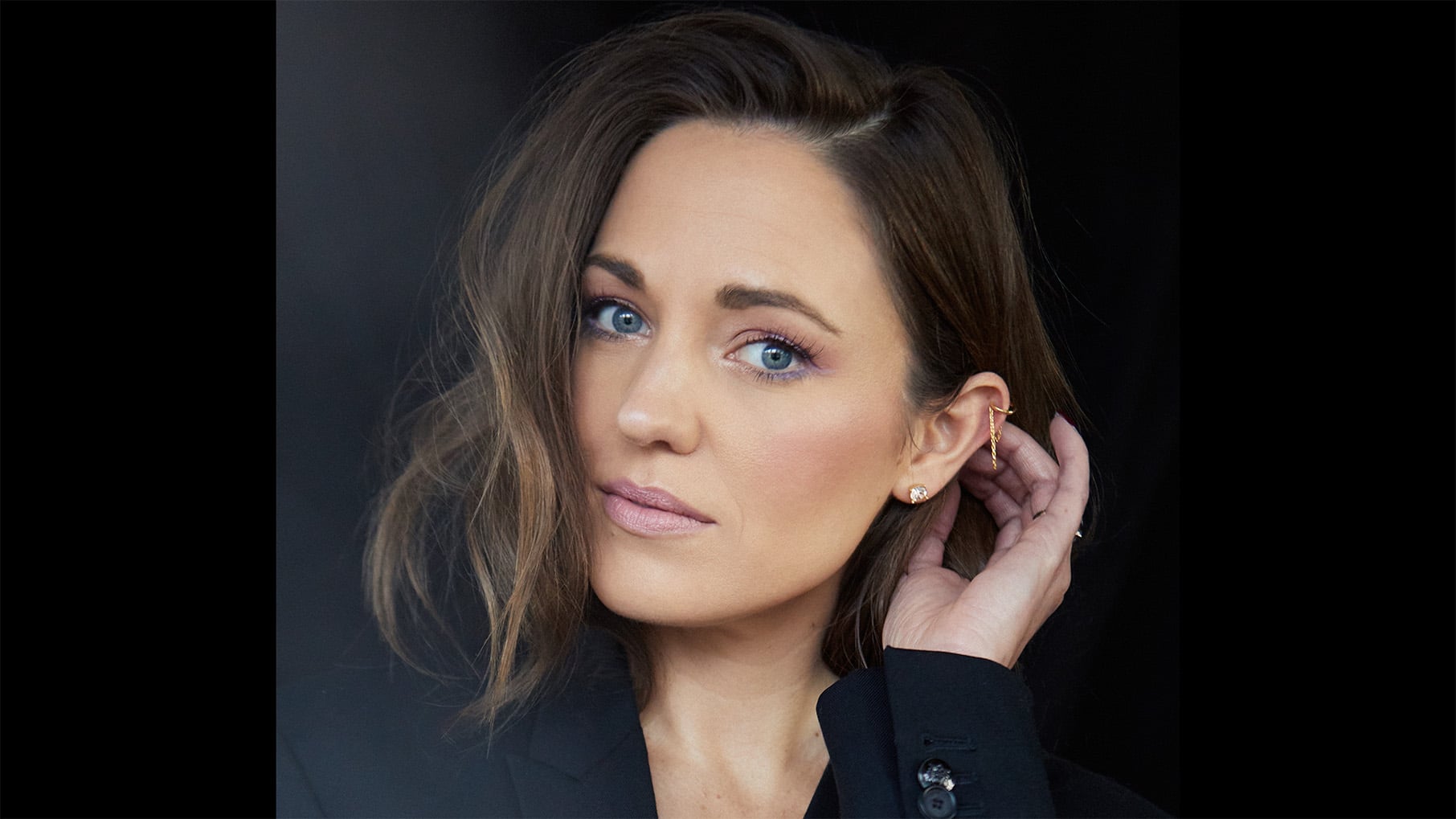 Laura Osnes with her hand behind her ear in a portrait
