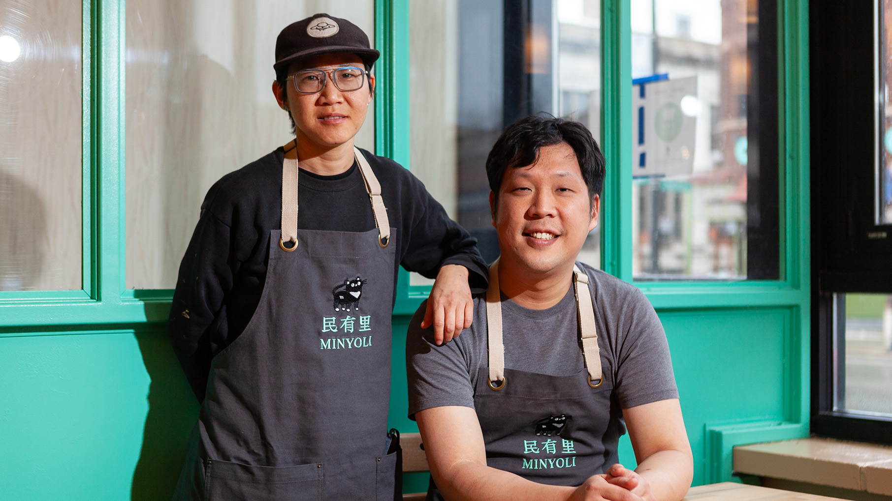 X Wang stands next to a seated Rich Wang as they smile for a portrait