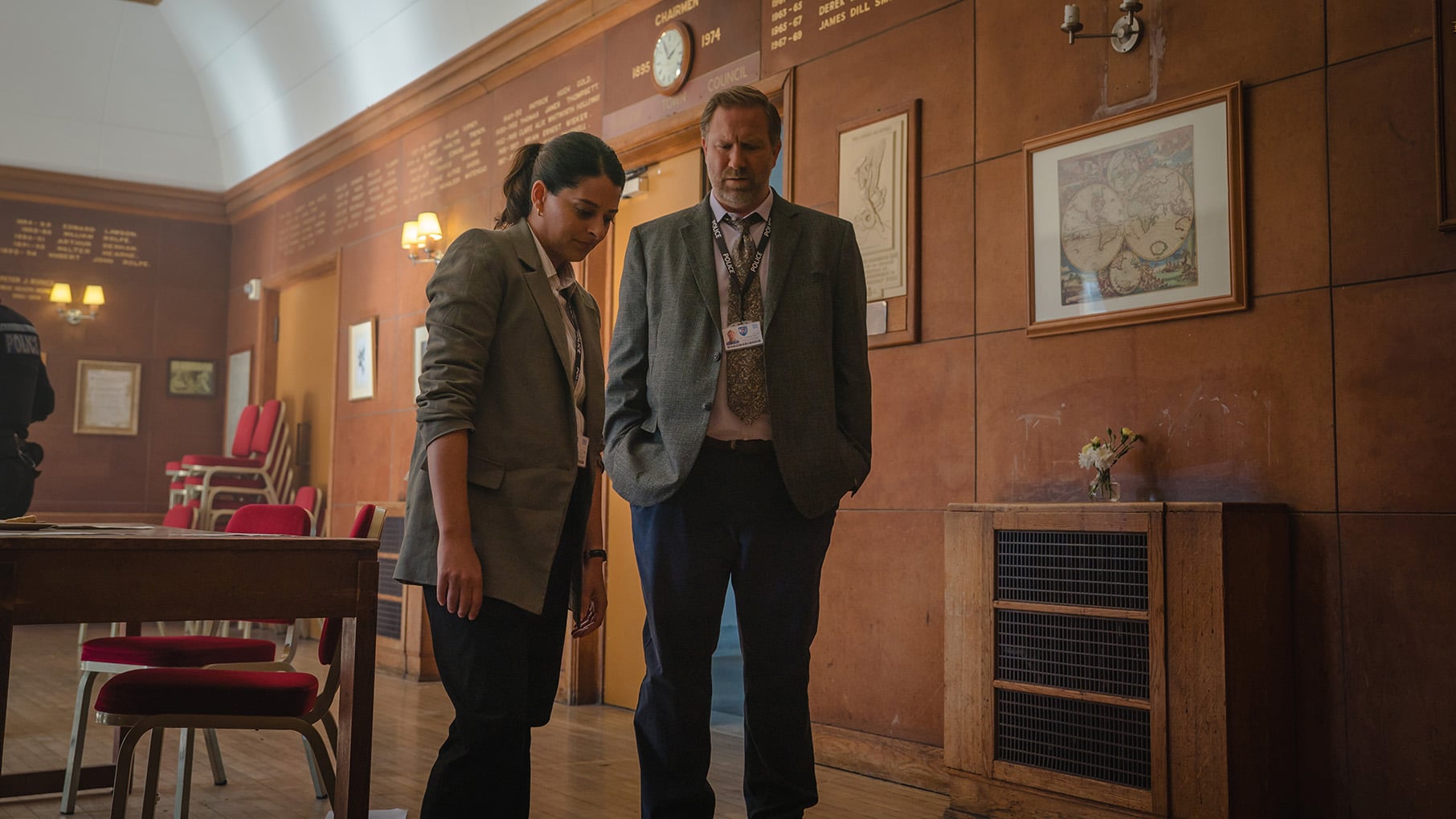Tanika and Brendan stand in a room looking down at something