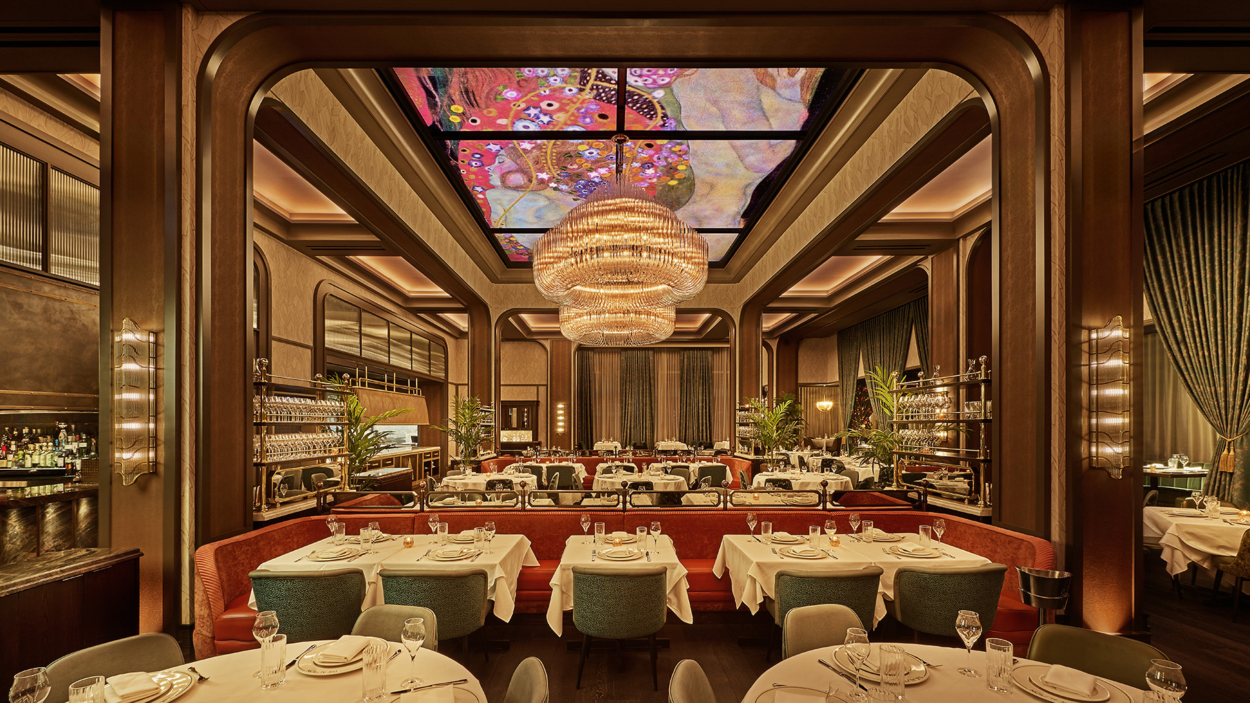 A large restaurant dining room with massive chandeliers and a digital ceiling displaying Klimt