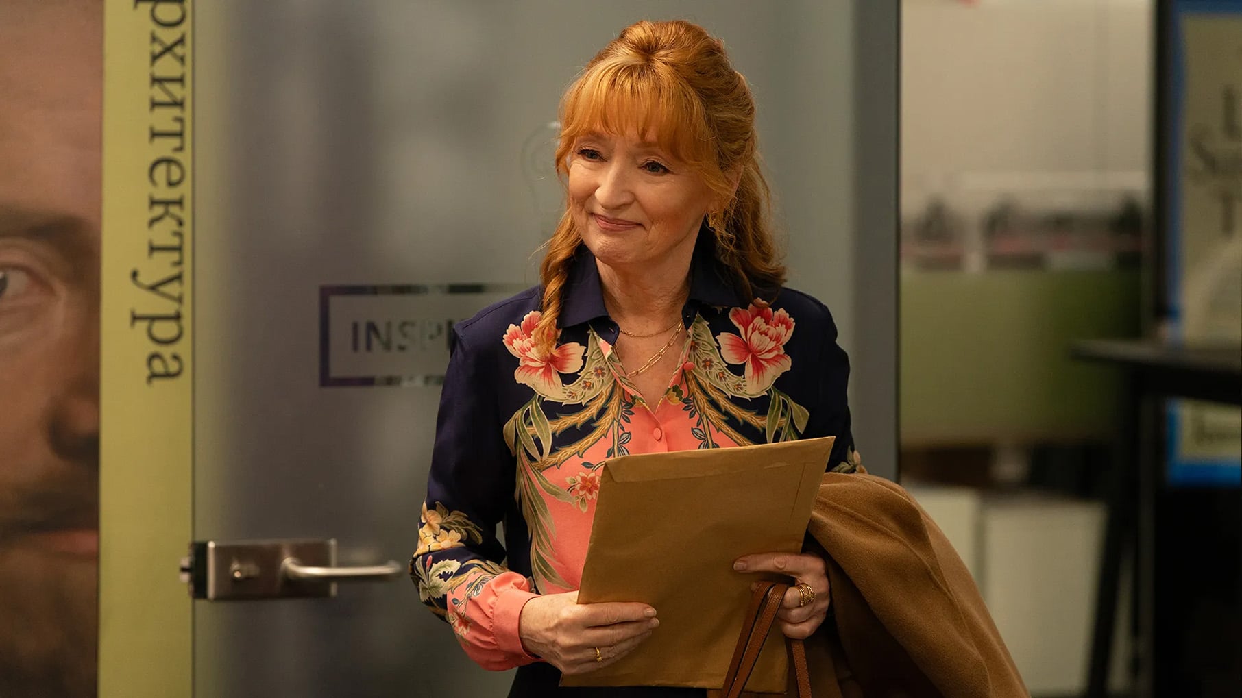 Susan Ryeland holds an envelope and her coat in an office