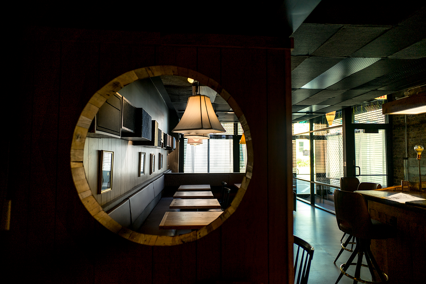 A shadowy restaurant space with a circular wood cut-out in the foreground